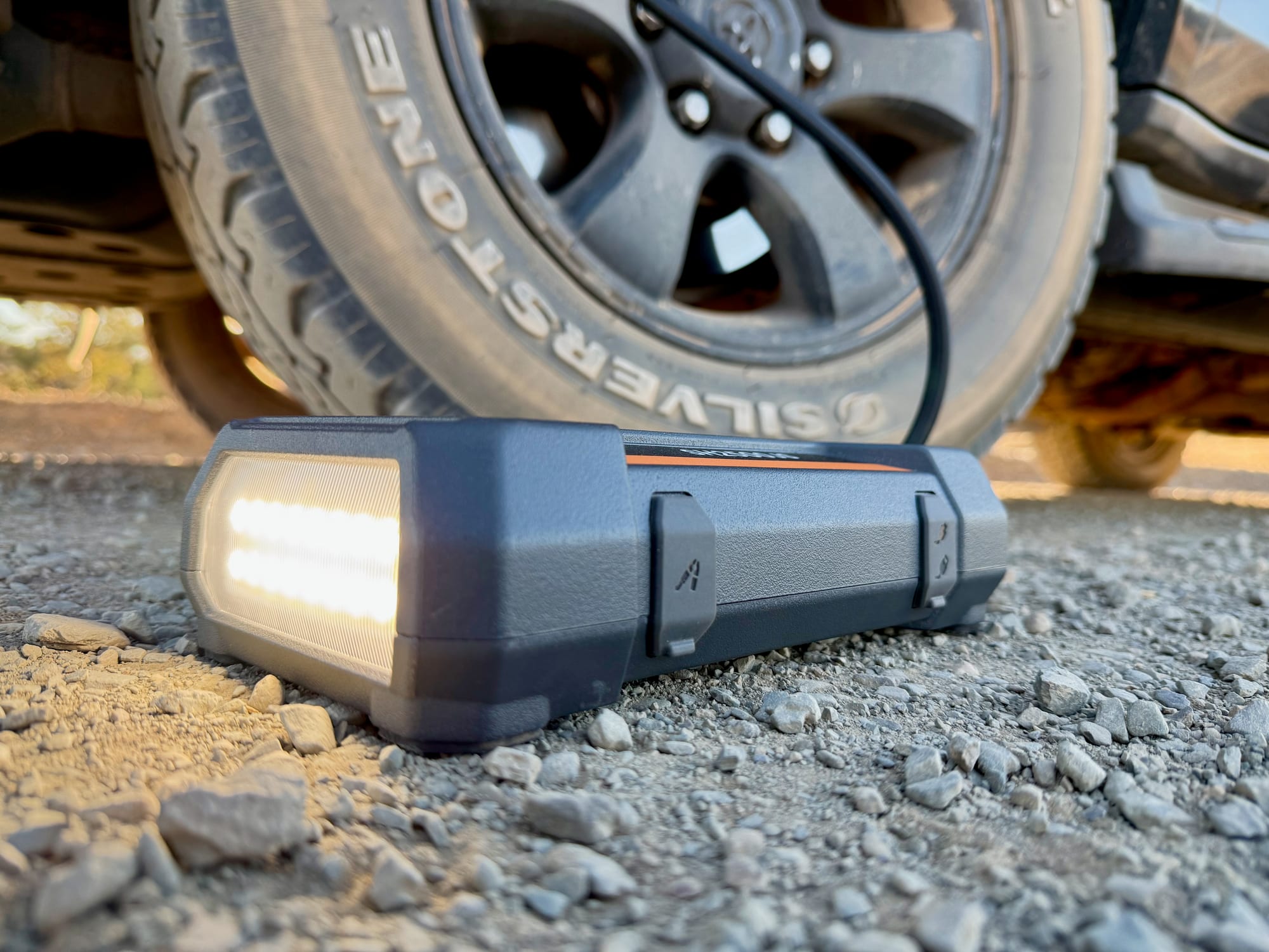 The San Hima on gravel next to a tyre with its LED light switched on