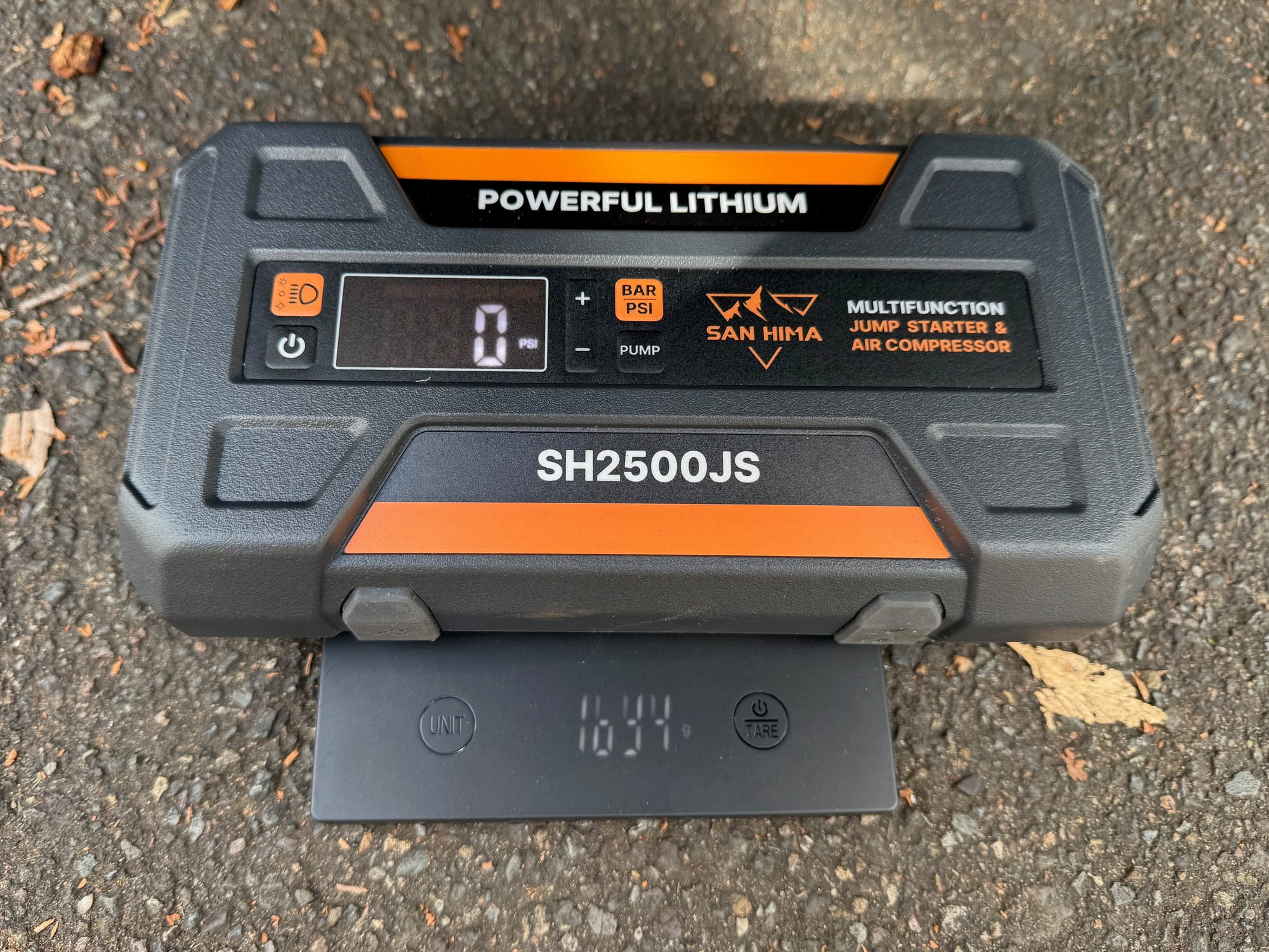 The San Hima jump starter on a scale showing 1634 g