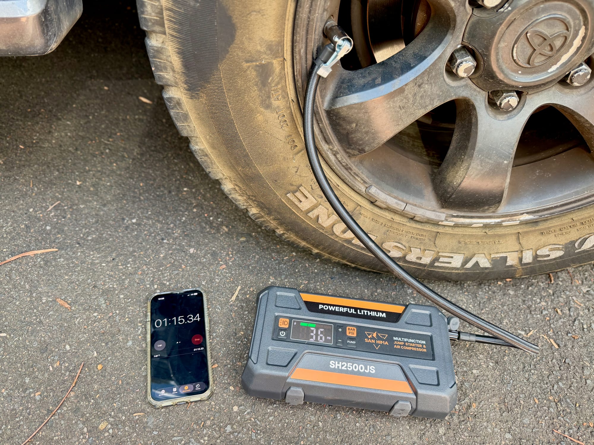 The San Hima pumping up a tyre of our Prado next to a phone running a stopwatch