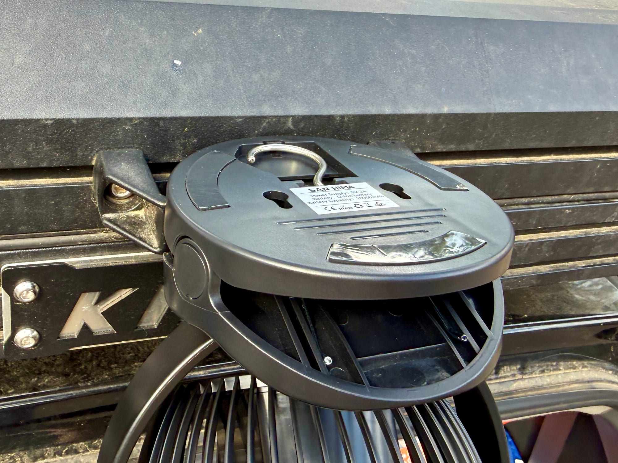 The clamp base of the San Hima fan gripping the edge of a rooftop tent, seen from below