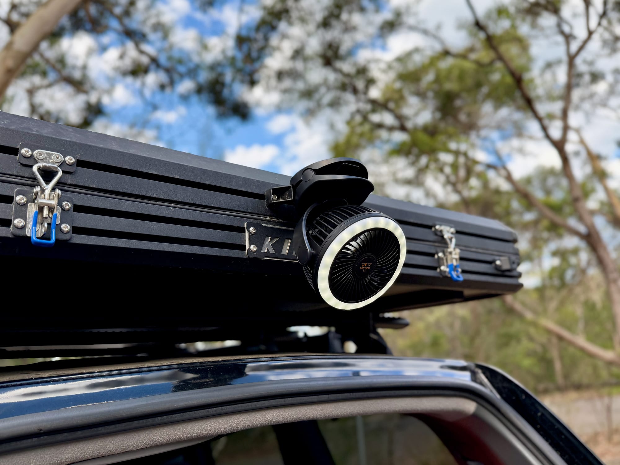 The San Hima clip fan clipped to the back edge of a rooftop tent, above the open rear door of a 4WD