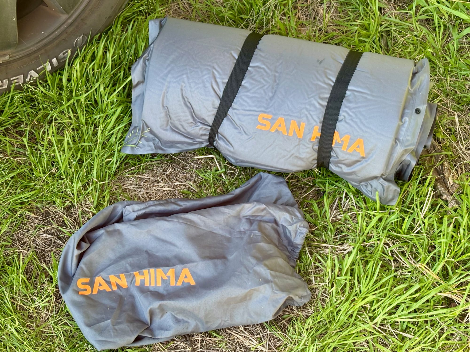The San Hima self-inflating mattress rolled up with two straps, next to its storage bag