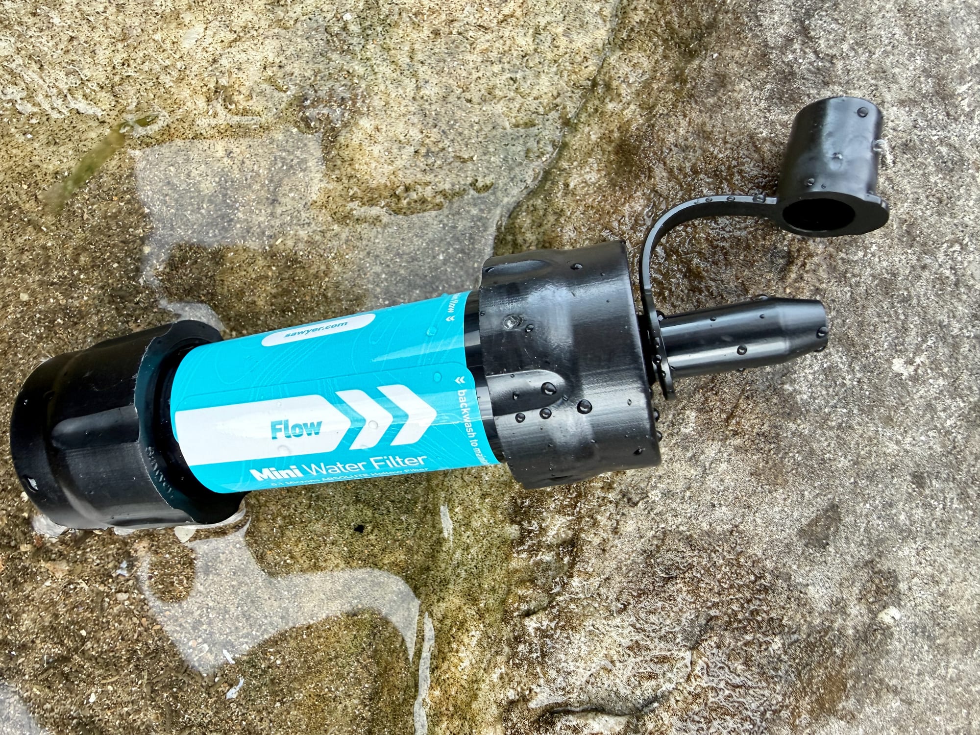 Close-up of the Sawyer Mini with its flow arrows and the push-pull cap on its strap