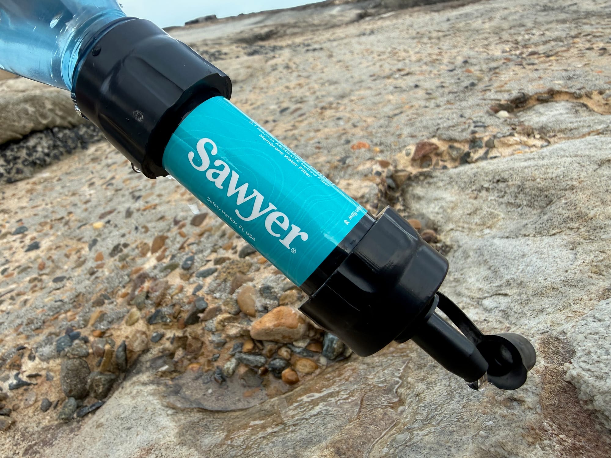 The Sawyer Mini screwed onto a plastic bottle and held upside down on a sandstone rock