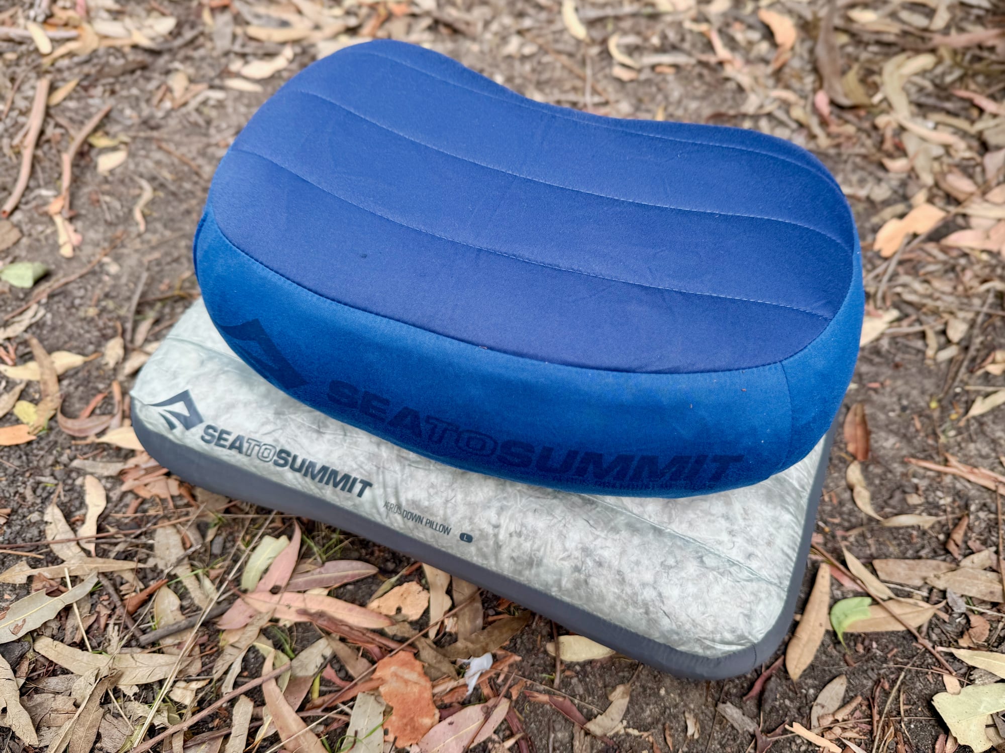 The blue Sea to Summit Aeros Premium pillow lying on top of the grey Aeros Down Pillow