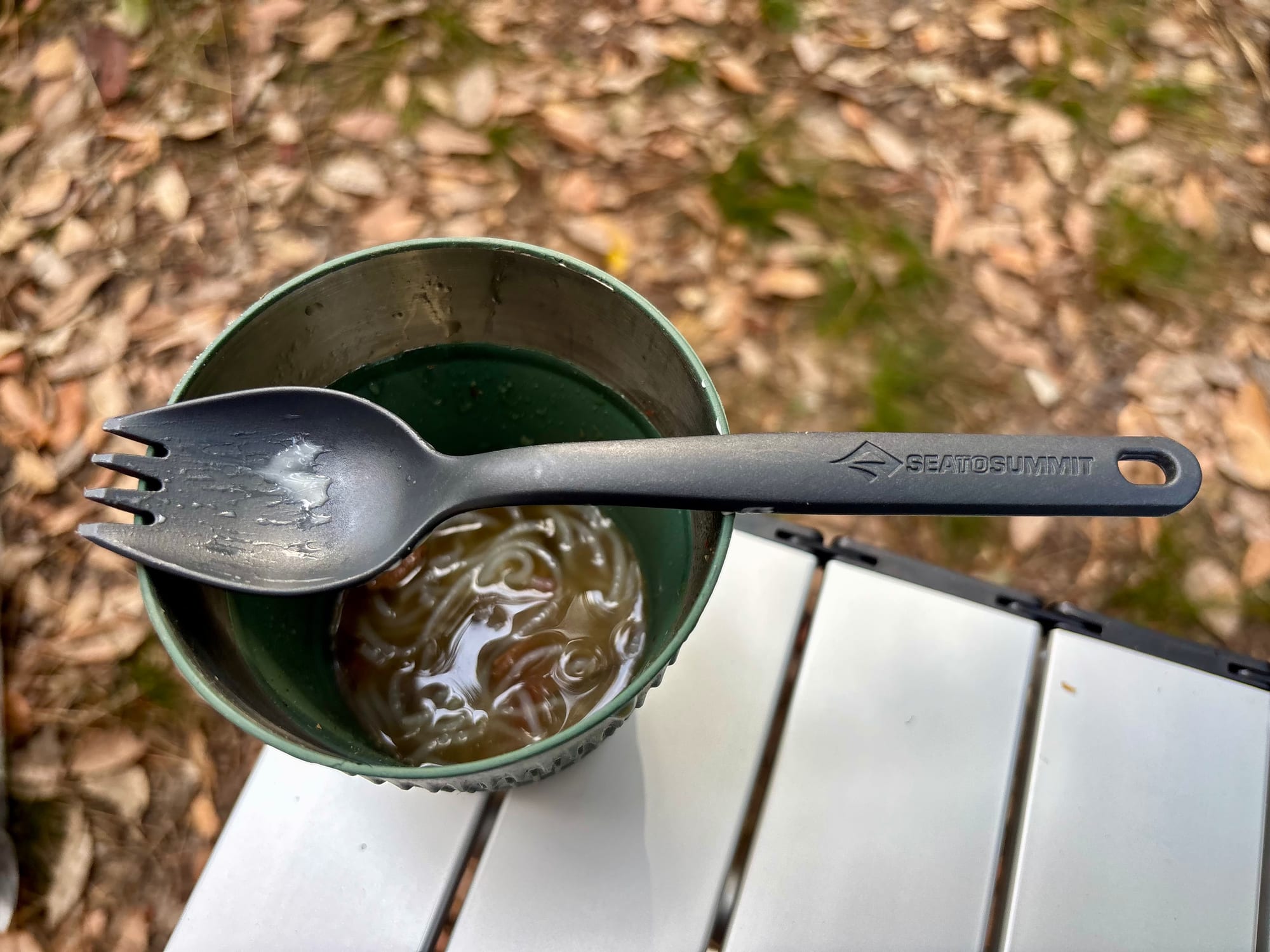 The Sea to Summit spork resting across a mug of noodle soup, seen from above