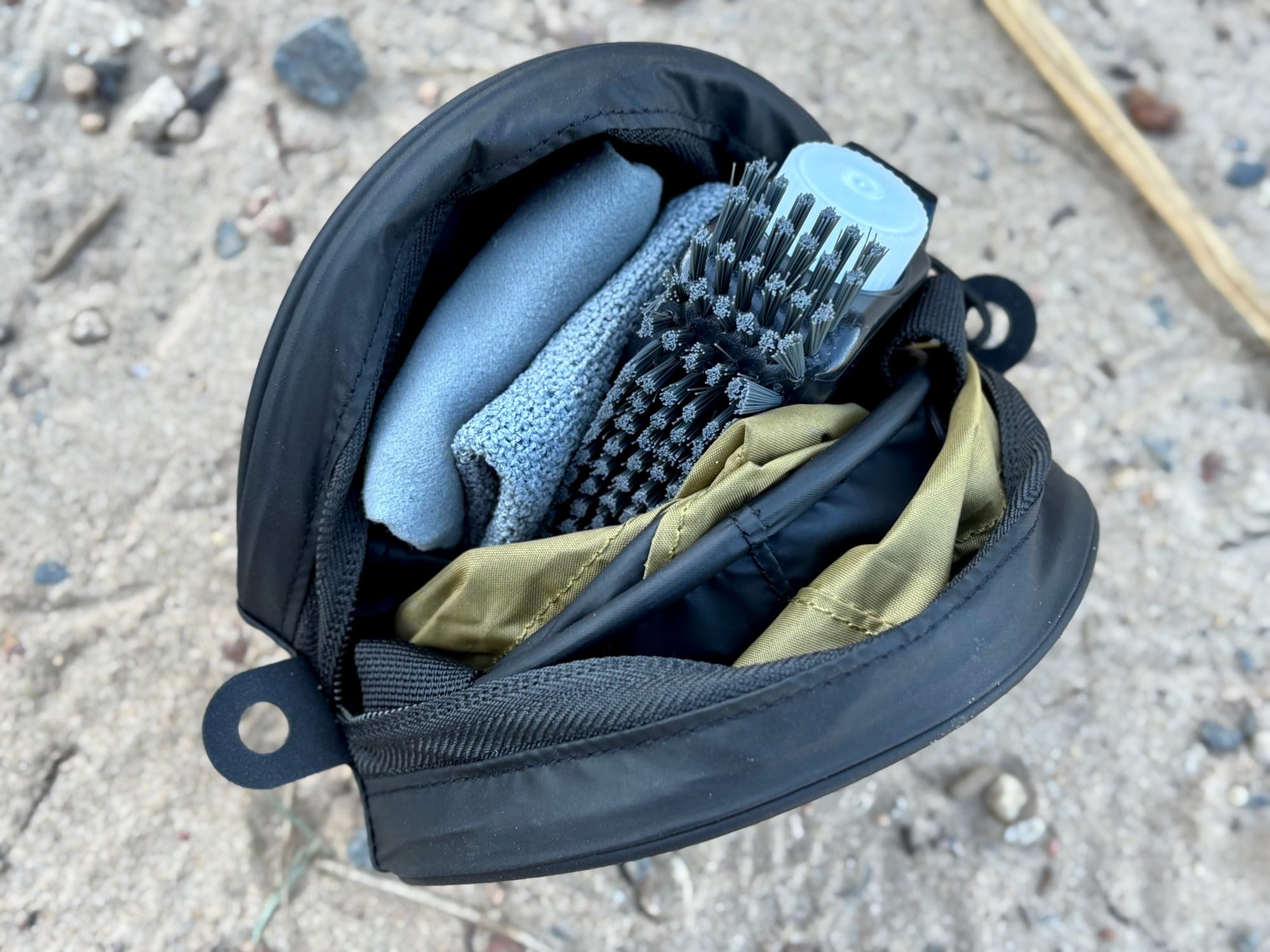 The Sea to Summit clean-up kit case opened, with the folded sink, washcloth and scrubber packed inside