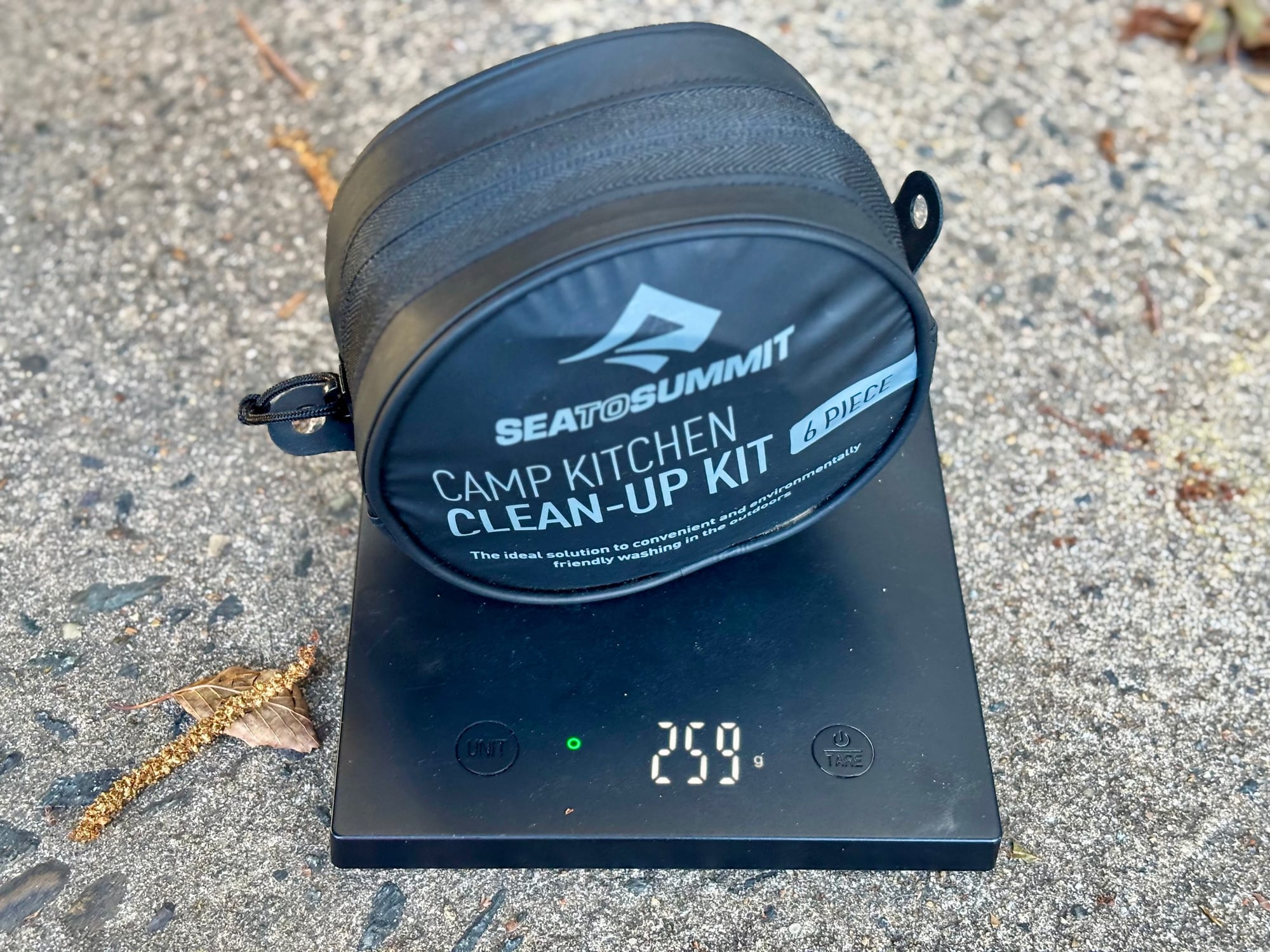 The Sea to Summit Camp Kitchen Clean-Up Kit in its case on a scale showing 259 g