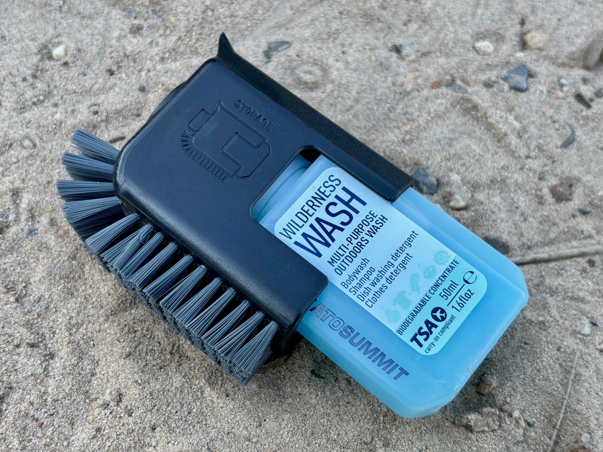 The scrubber with its nylon bristles clipped around a bottle of Wilderness Wash