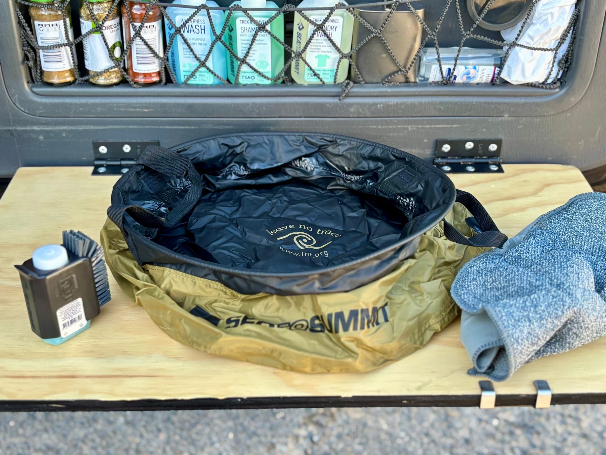 The Sea to Summit kitchen sink set up on a slide-out table at the back of a 4WD, with the scrubber, soap and washcloth