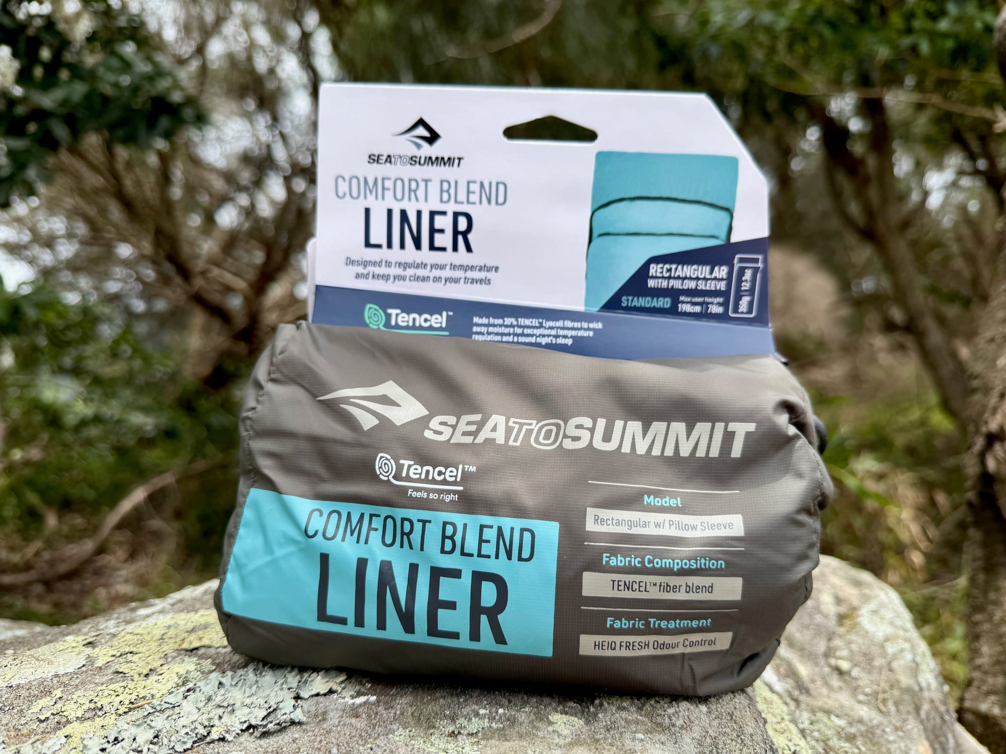 The Sea to Summit Comfort Blend liner in its box and stuff sack on a rock