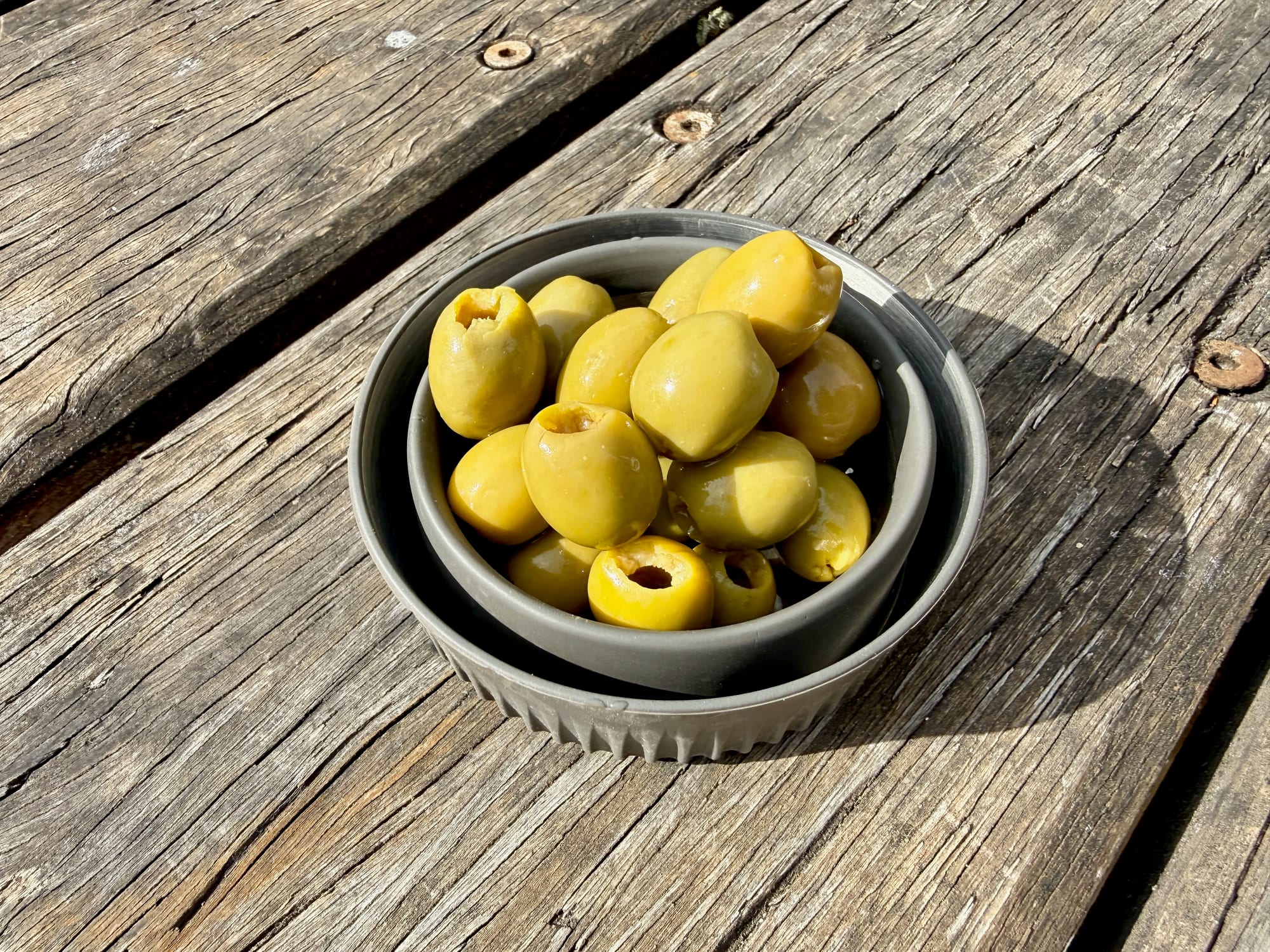 A collapsed Detour mug used as a small bowl for olives on a timber table