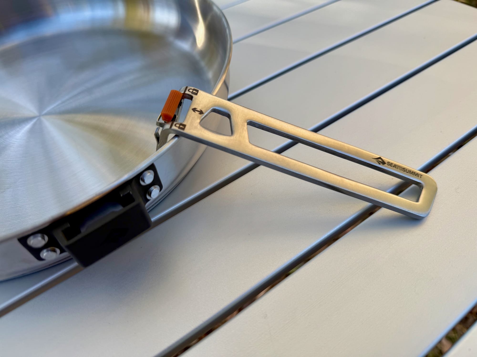 The Click-Safe handle of the Sea to Summit Detour Pan folded out and locked, with its orange release tab