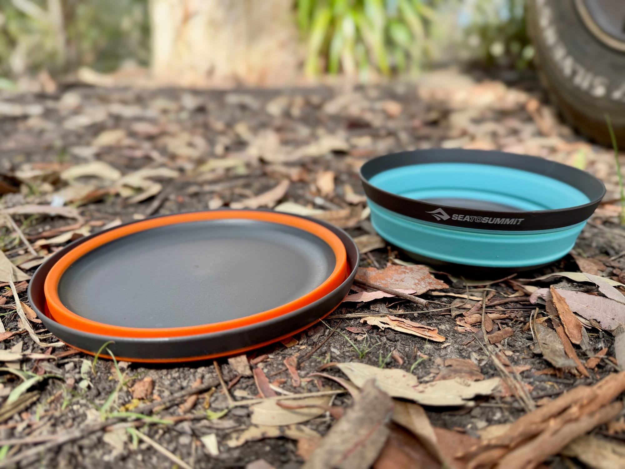 A collapsed orange Large Frontier bowl next to an open aqua Medium on the ground