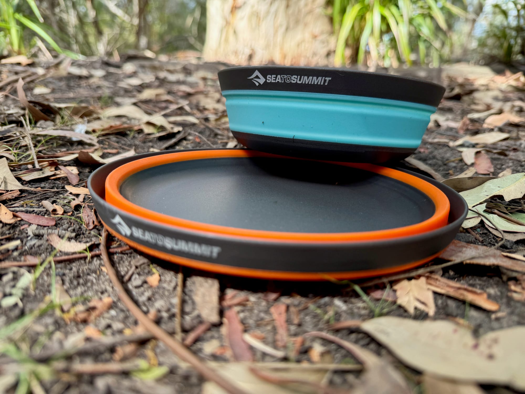 A collapsed aqua Medium Frontier bowl stacked on a collapsed orange Large