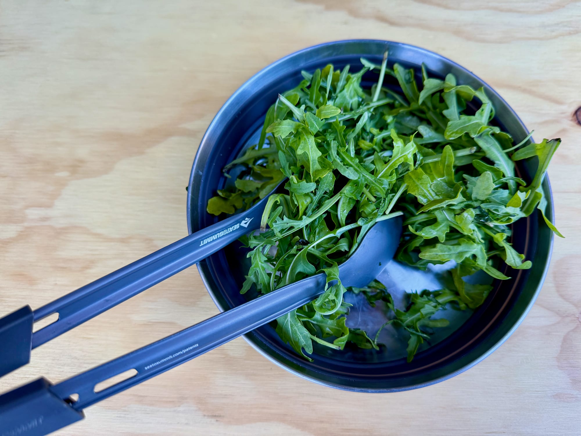 Serving salad with the Frontier UL spoon and spork clipped together as tongs