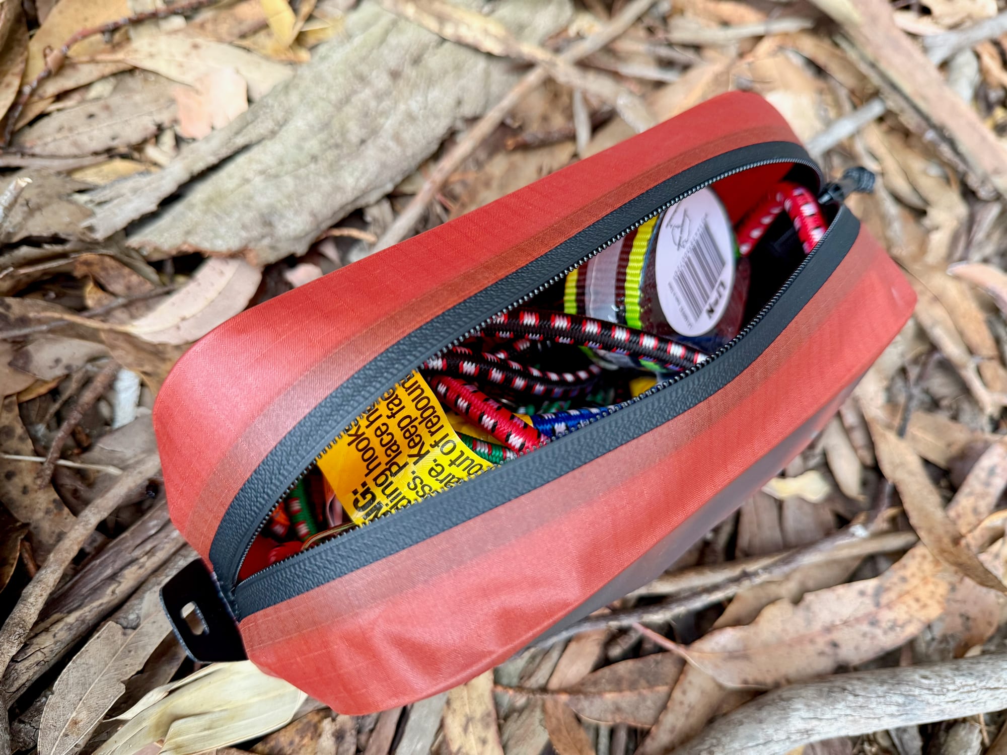The small red cube open, with bungee cords and straps inside