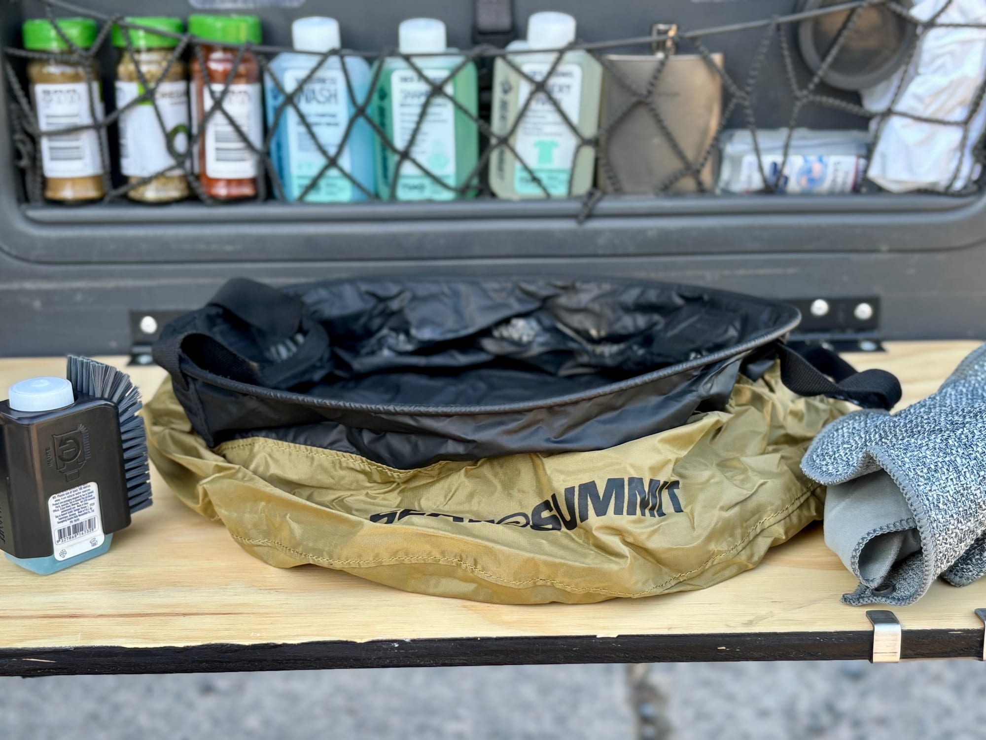 The Sea to Summit Kitchen Sink on a slide-out table at the back of a Prado, with a brush, soap and washcloth