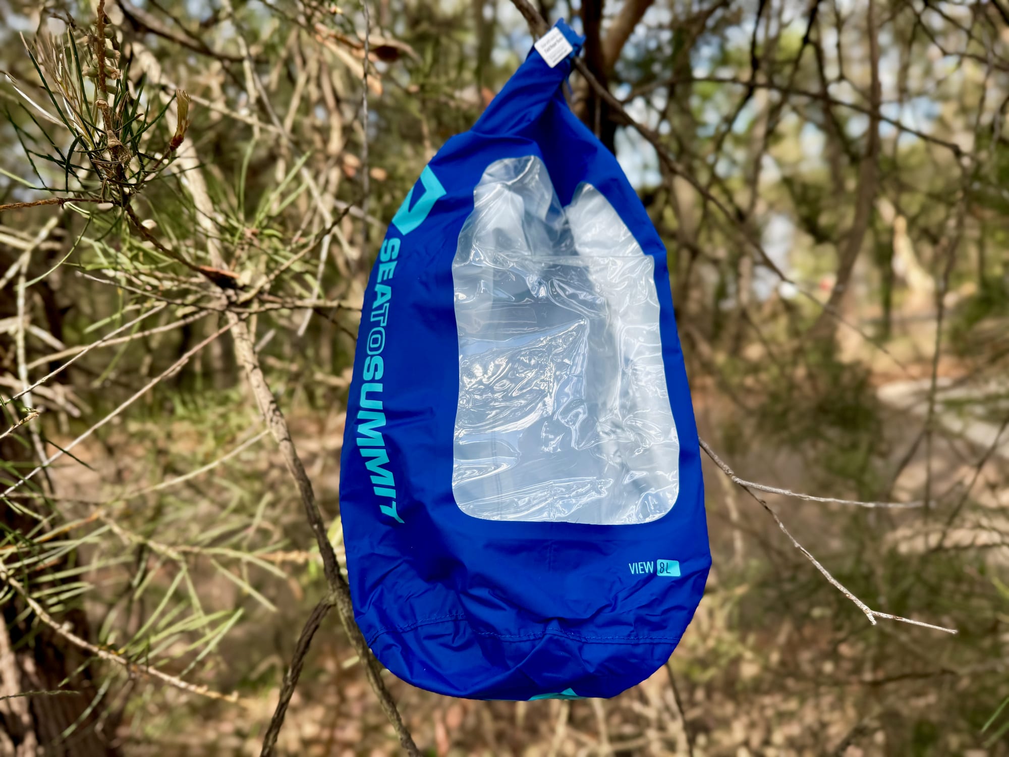 The empty Dry Bag View hanging from a branch, showing the clear window