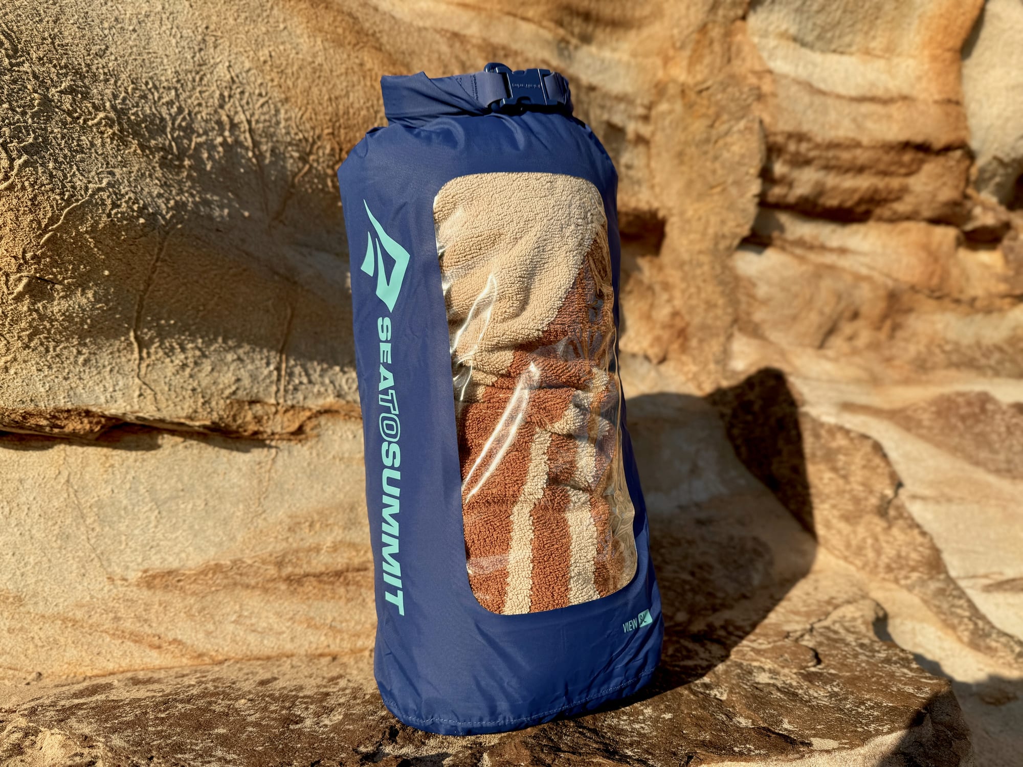 The Dry Bag View 8L with a whole thick beach towel inside, seen through the window