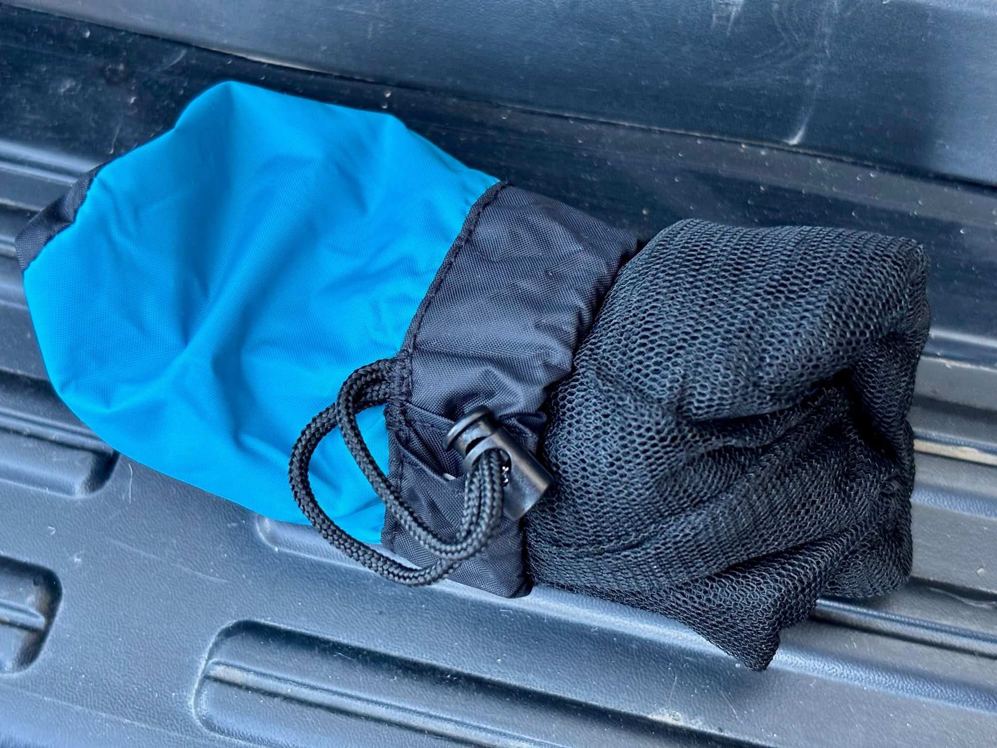 The black netting of the Sea to Summit Head Net half pushed into its blue stuff sack