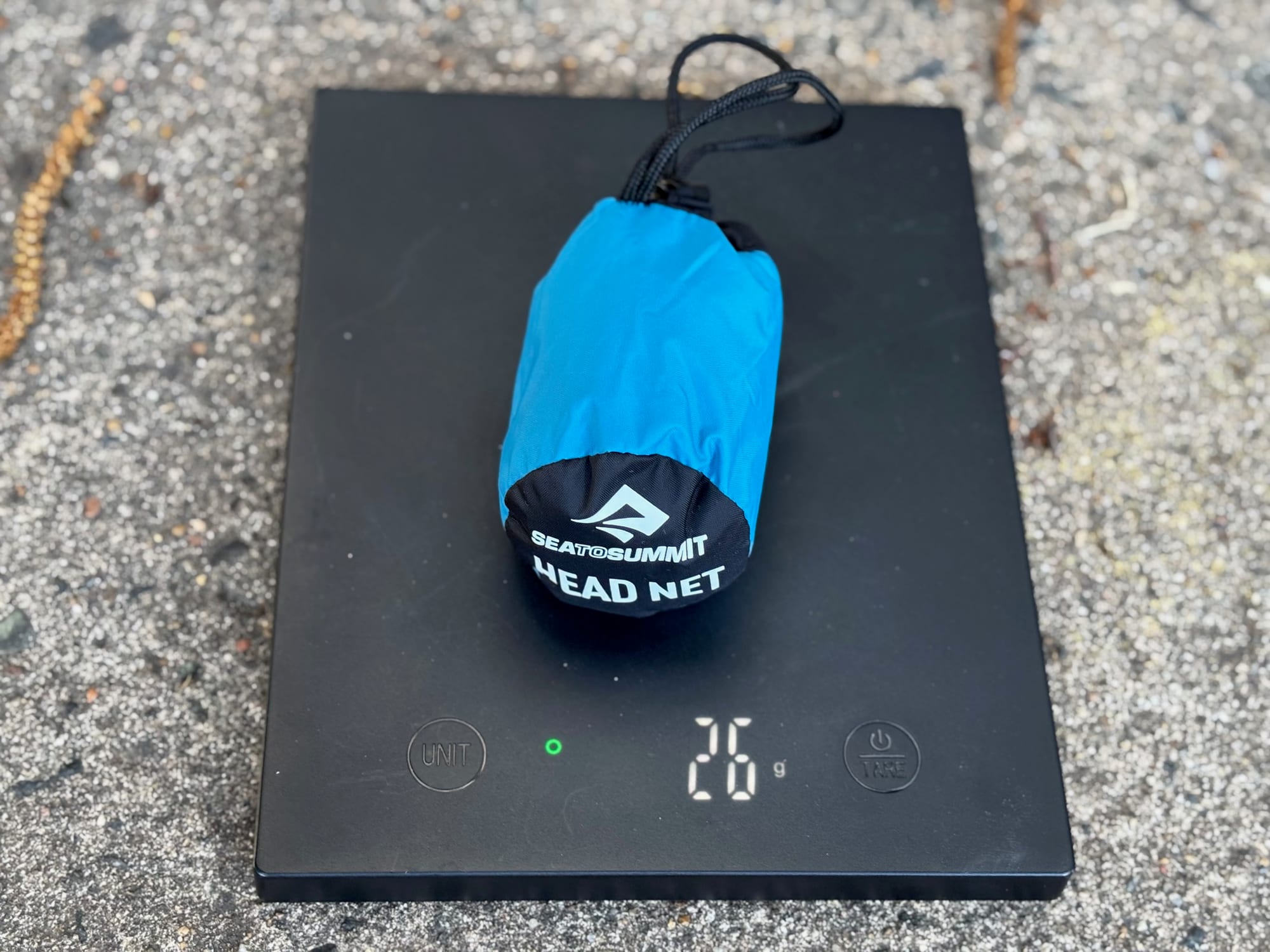 The Sea to Summit Head Net in its stuff sack on a scale showing 26 g
