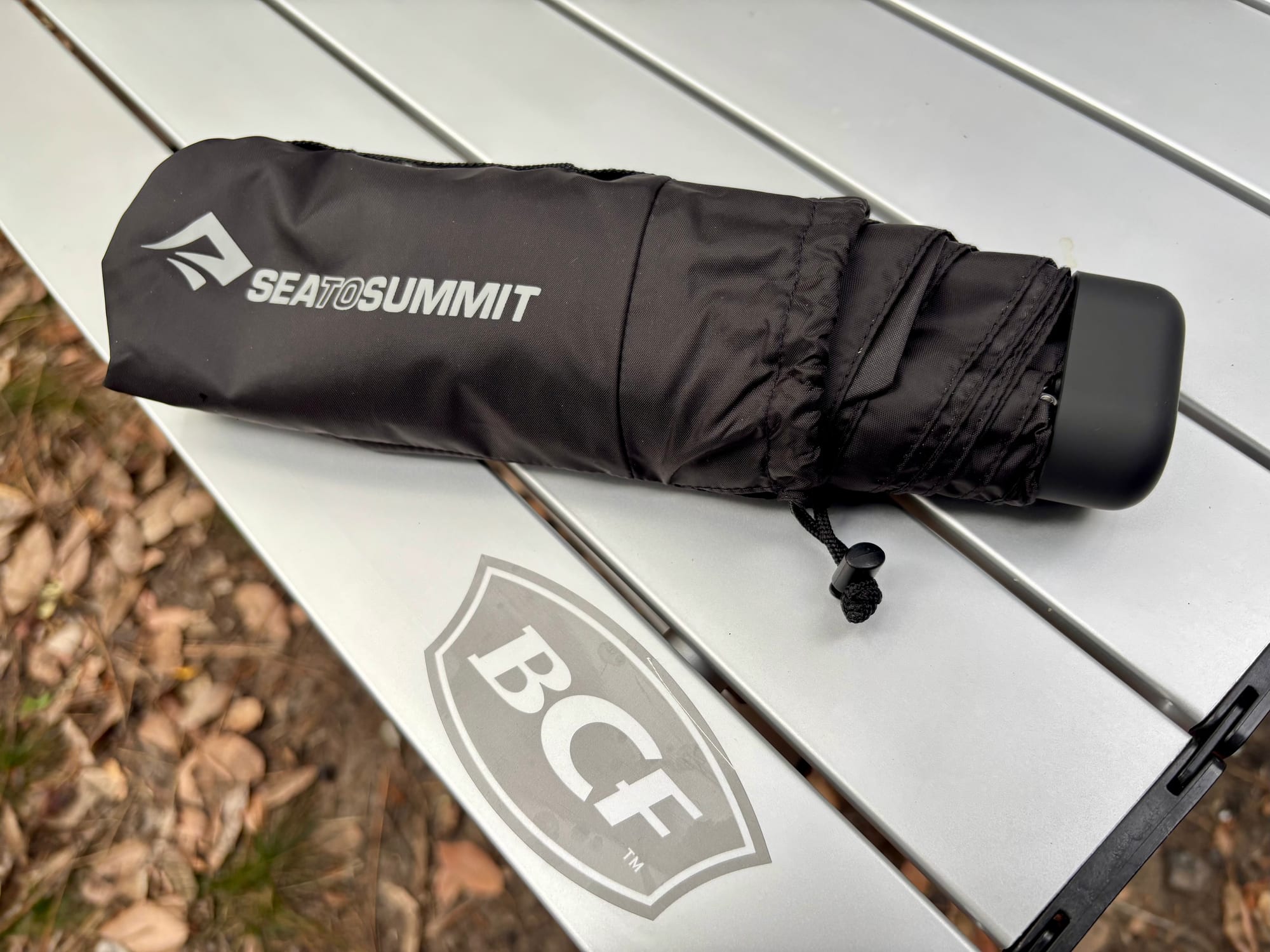 The folded Sea to Summit Pocket Umbrella half out of its drawstring pouch
