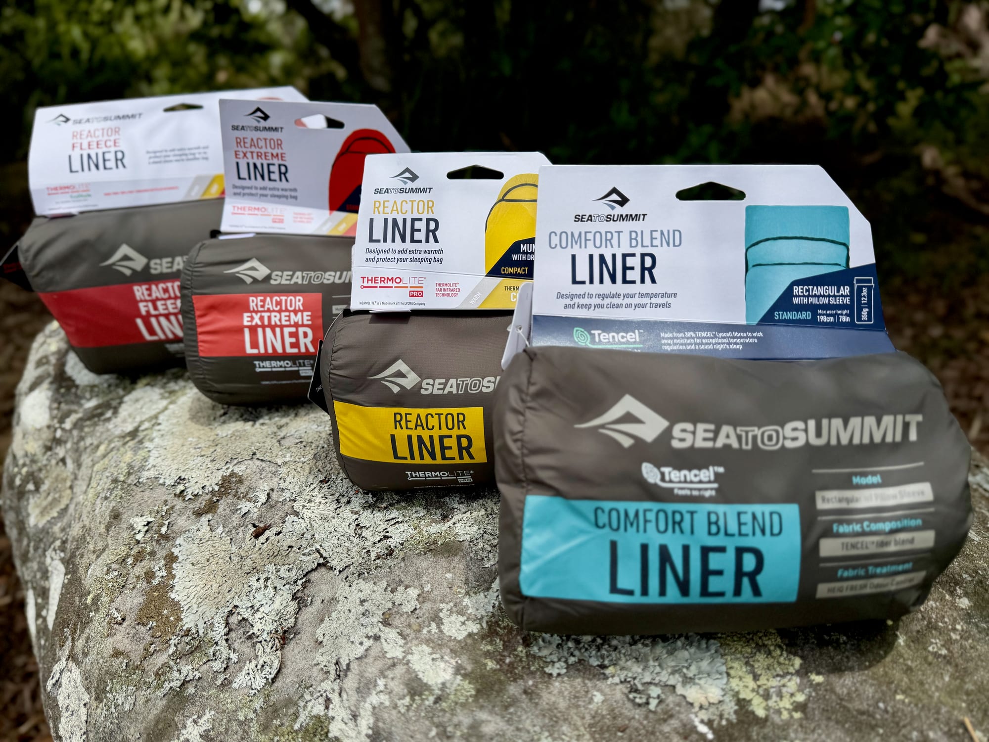 All four Sea to Summit liners packed in their stuff sacks on a rock: the Reactor Fleece, Reactor Extreme, Reactor and Comfort Blend