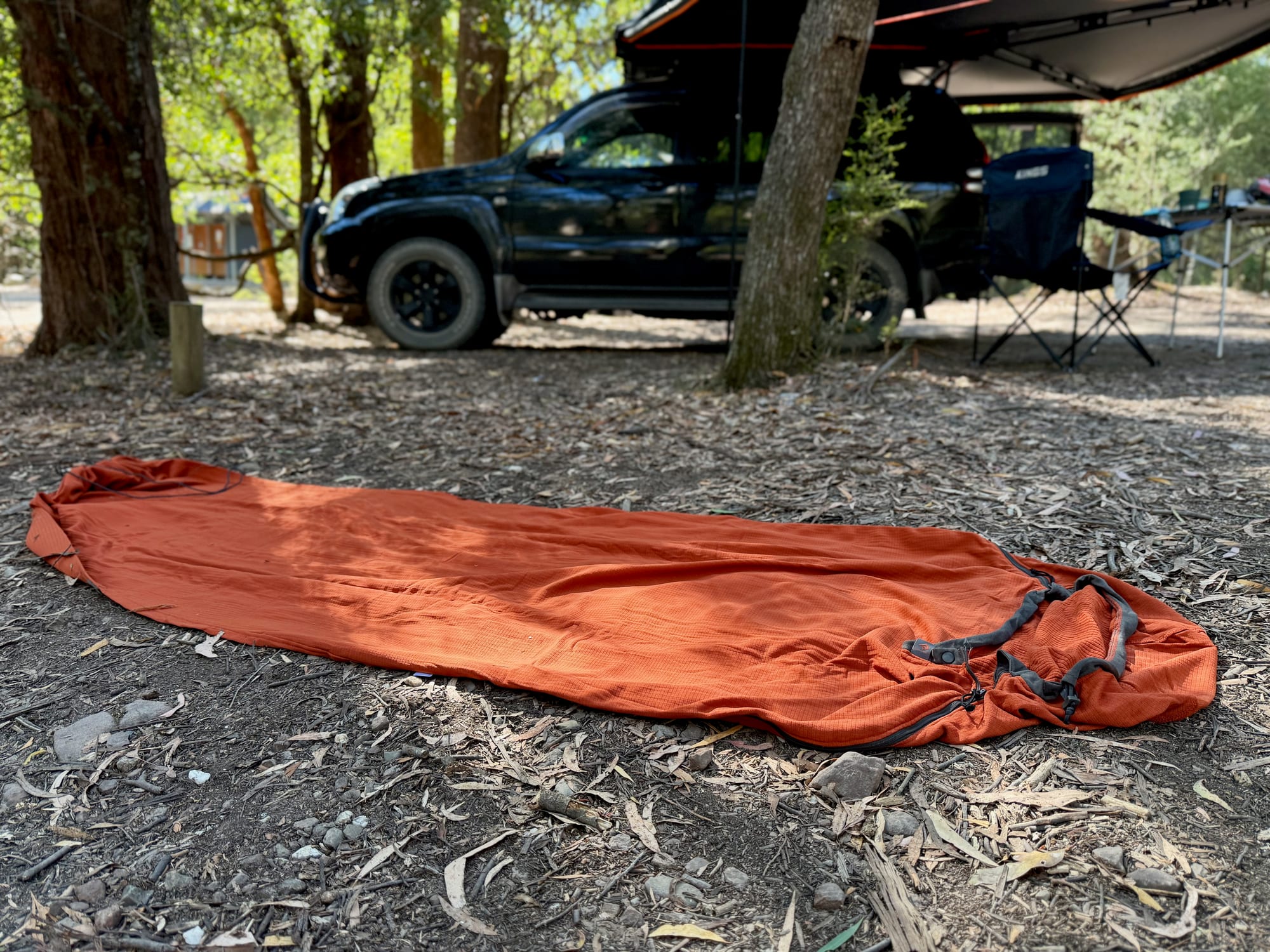 The Reactor Fleece liner laid out on the ground at camp, with our Prado, rooftop tent and awning behind
