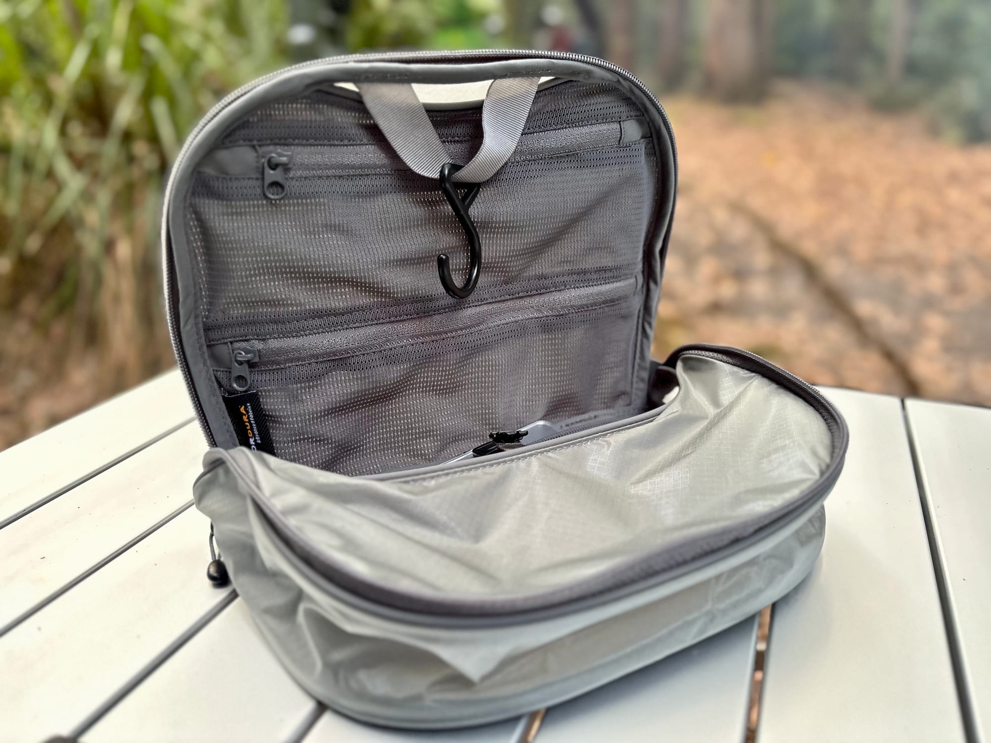 The Sea to Summit Hanging Toiletry Bag opened up on a camp table, with its hanging hook