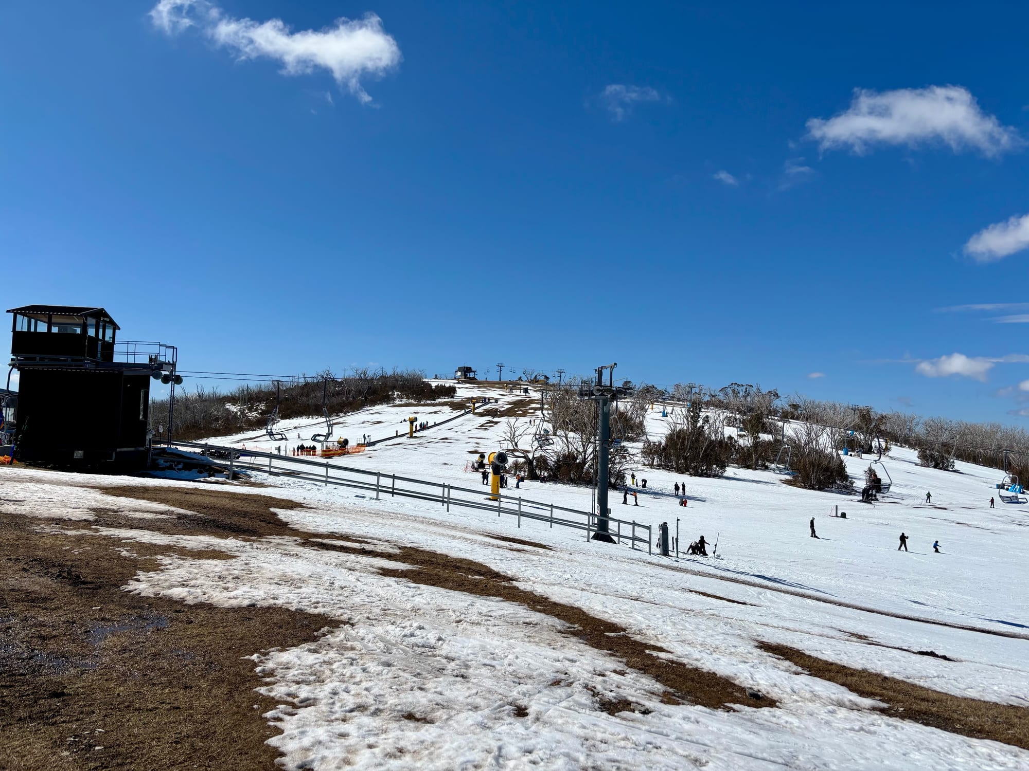 A chairlift and snow guns on the slopes at Selwyn Snow Resort, with skiers on the snow