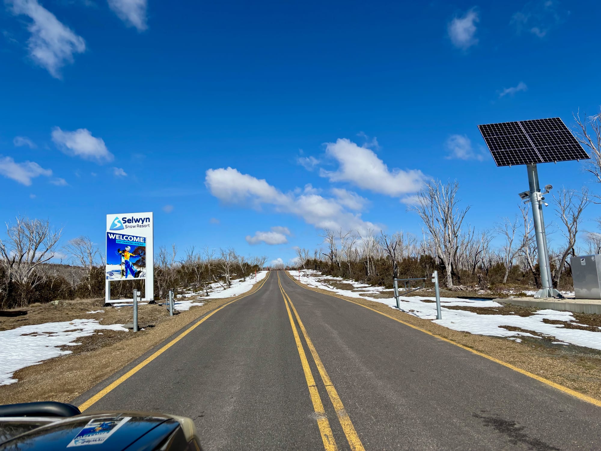 The sealed road in to Selwyn Snow Resort, with the welcome sign and snow beside the road