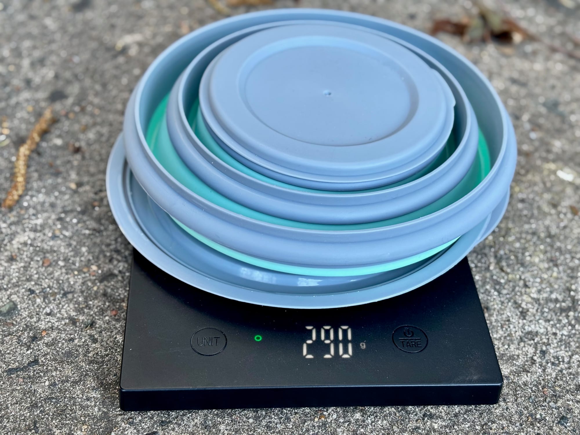 The three silicone bowls folded flat and nested, on a kitchen scale showing 290 g