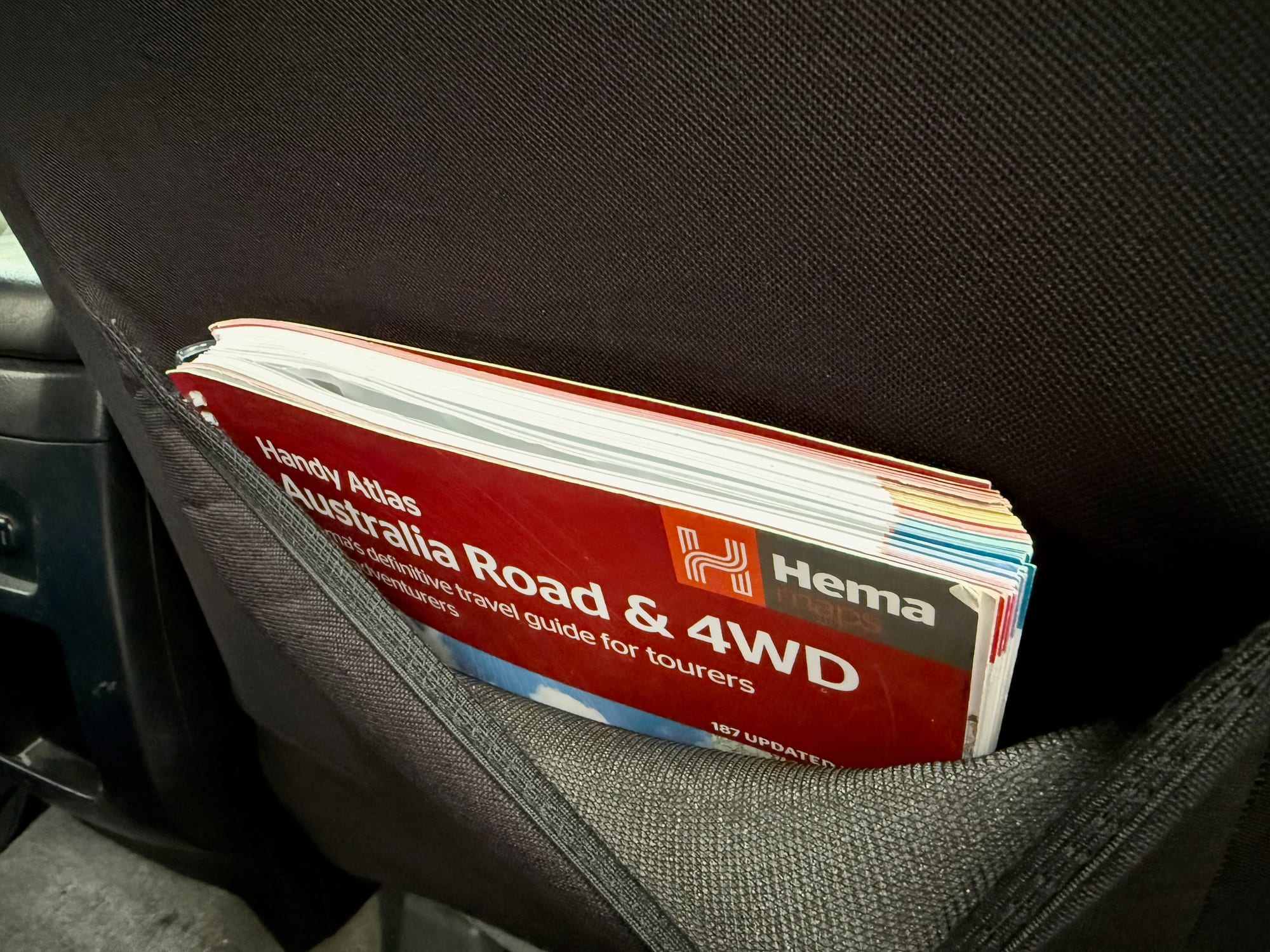 A Hema Australia Road and 4WD atlas in the pocket on the back of the Skechers seat cover
