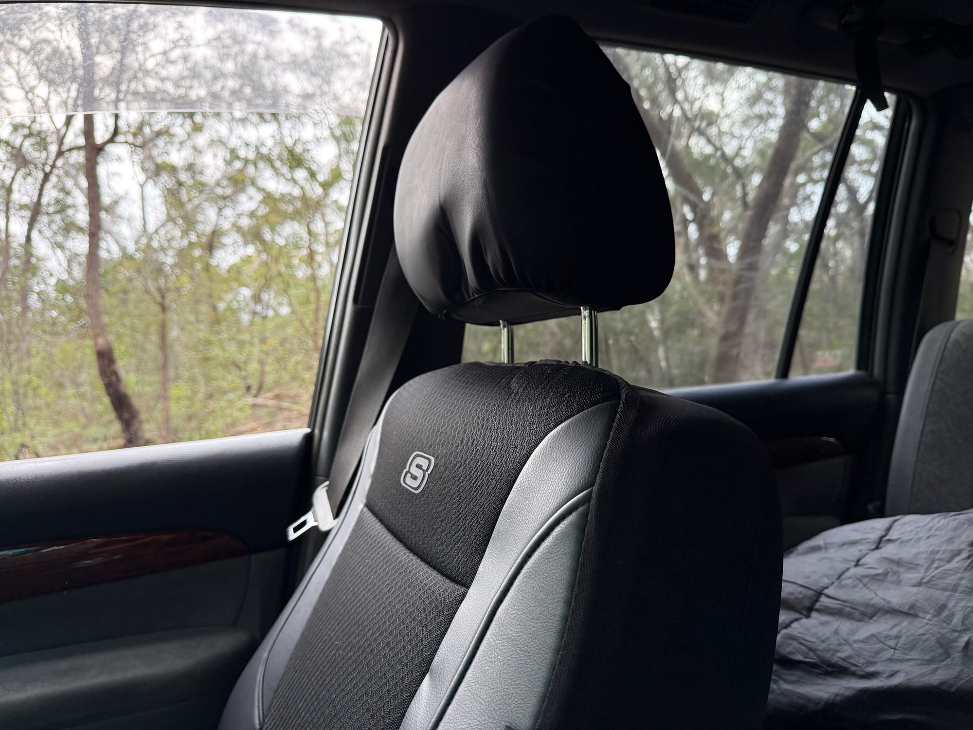 A black Skechers seat cover with its headrest cover on the front seat of our Prado