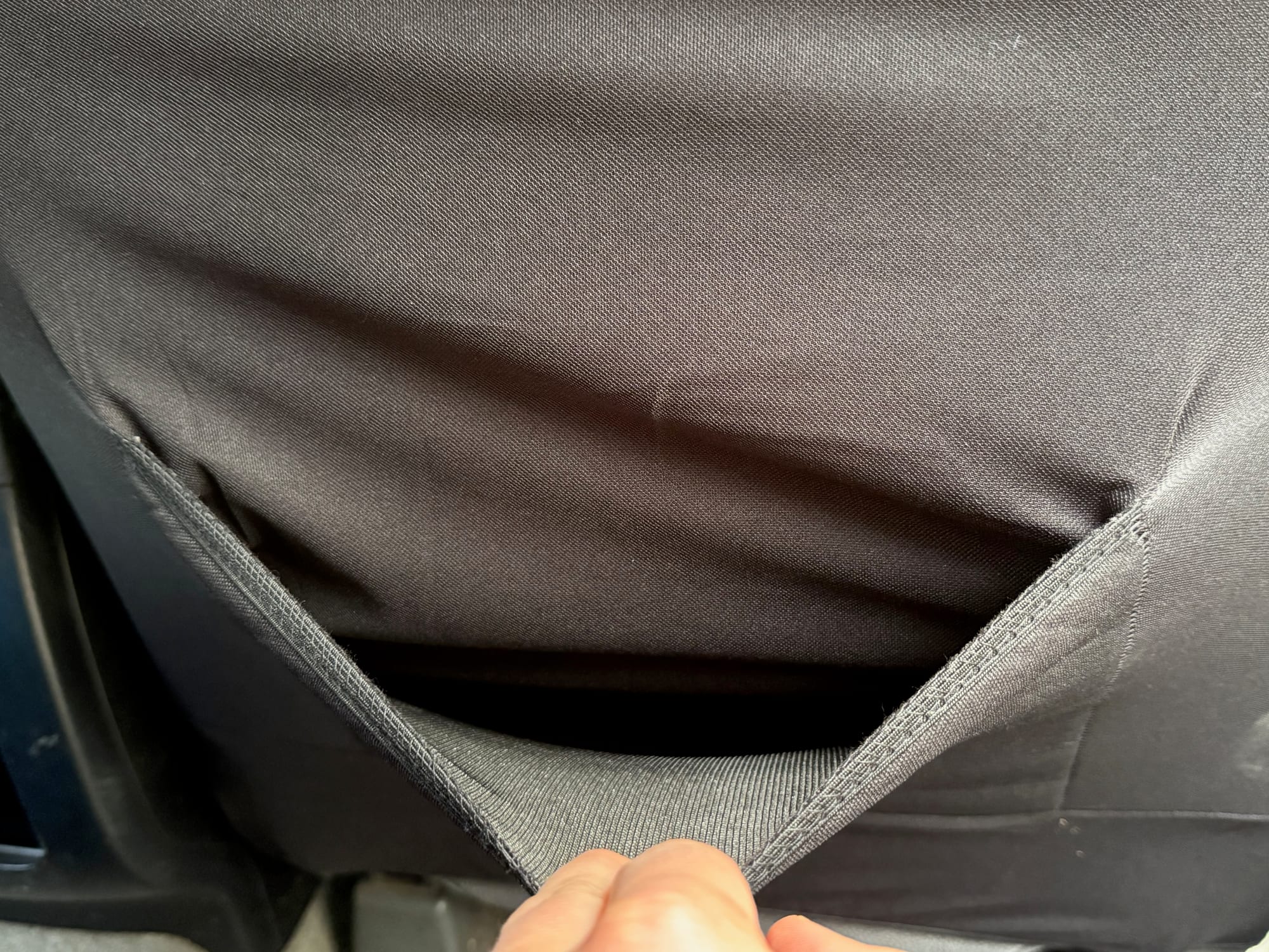 The thinner stretch fabric on the back of the Skechers seat cover, pulled back by hand