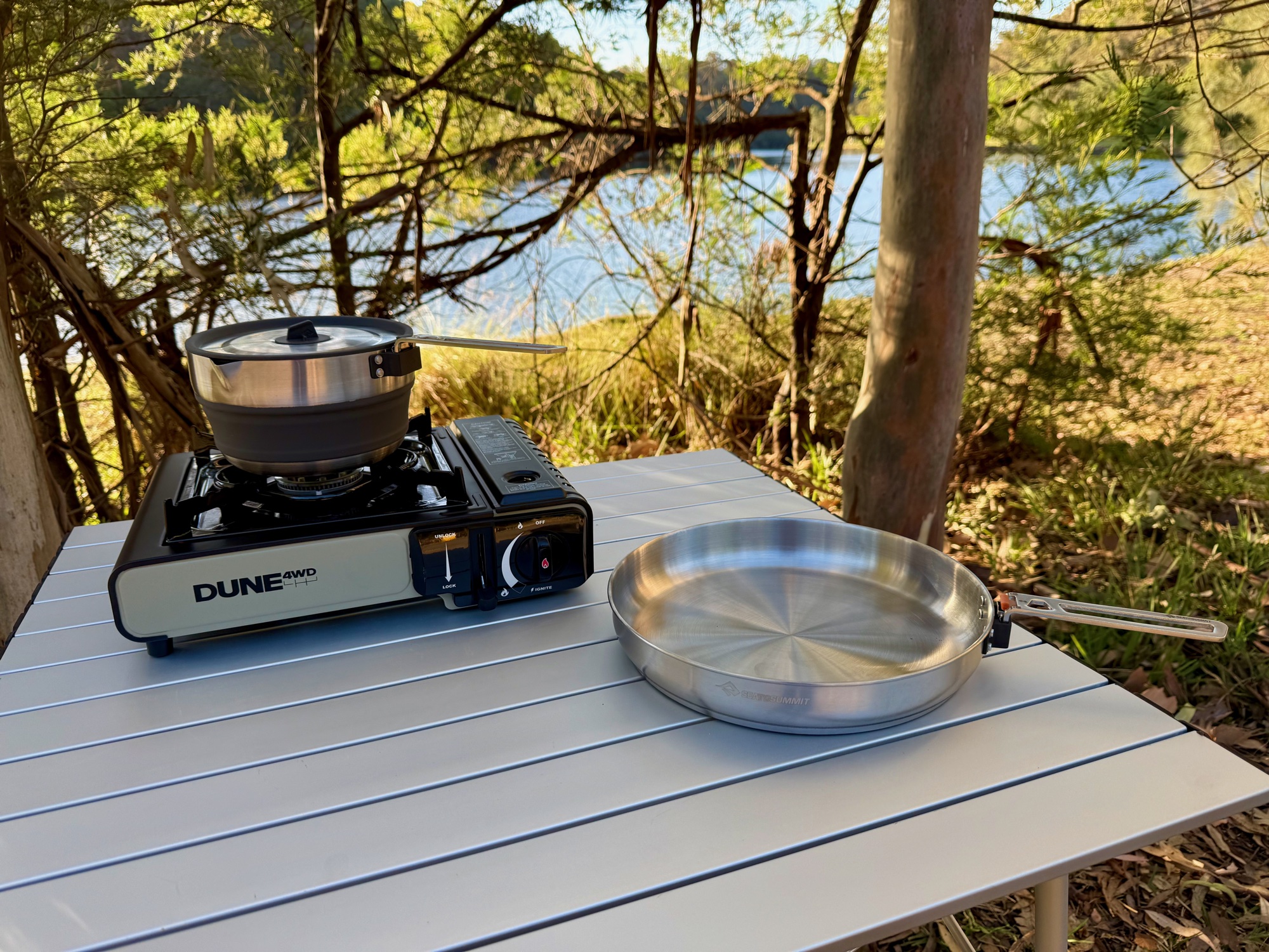 The Dune 4WD stove with a pot, and a frying pan beside it, on the Spinifex table top
