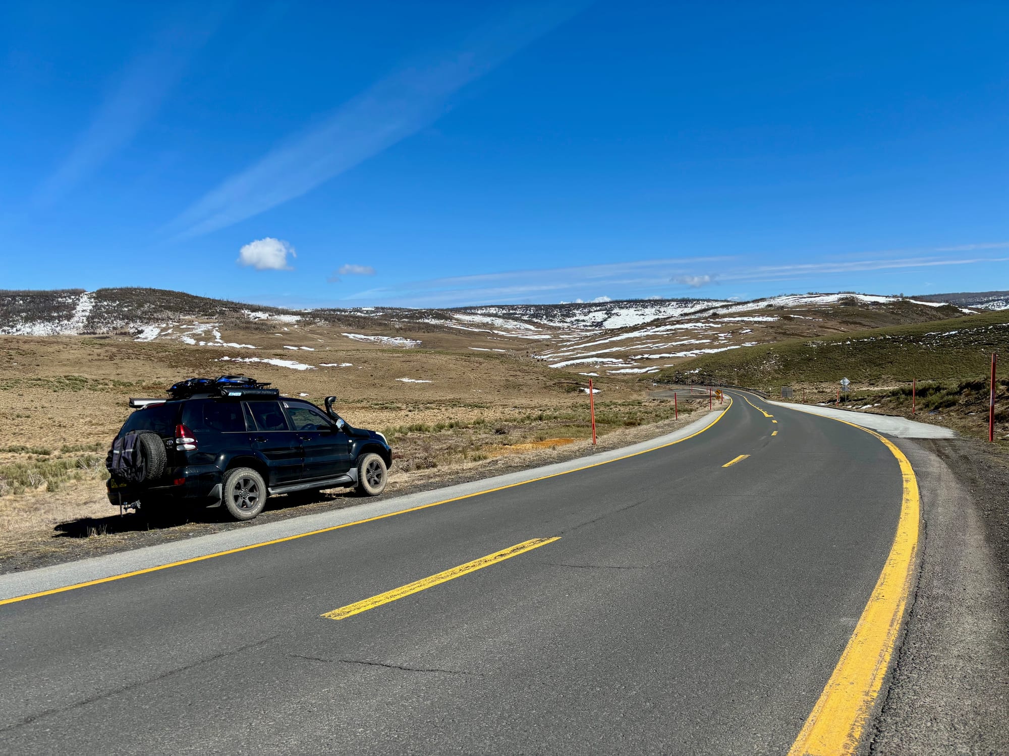 Link Road on the way up to Three Mile Dam, with our 4WD beside the road and snow on the hills