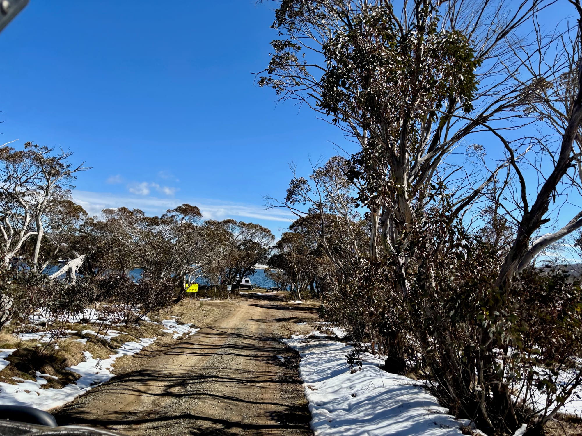 The gravel track into Three Mile Dam Campground, with snow along the edges