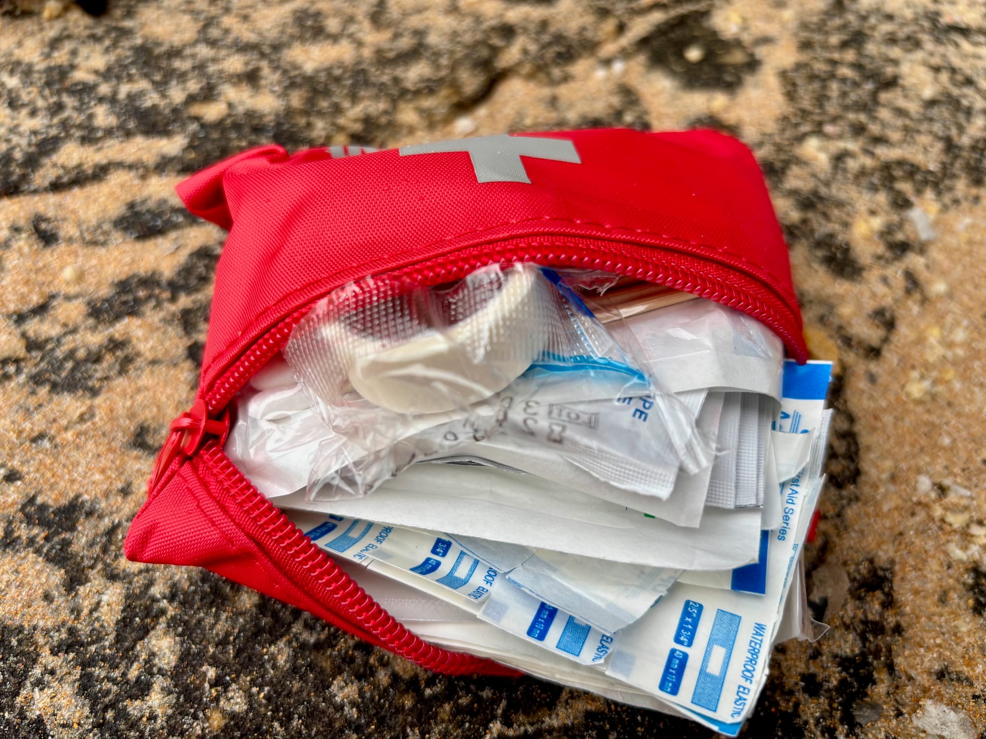 The small red zip pouch of first aid items, open and full of dressings