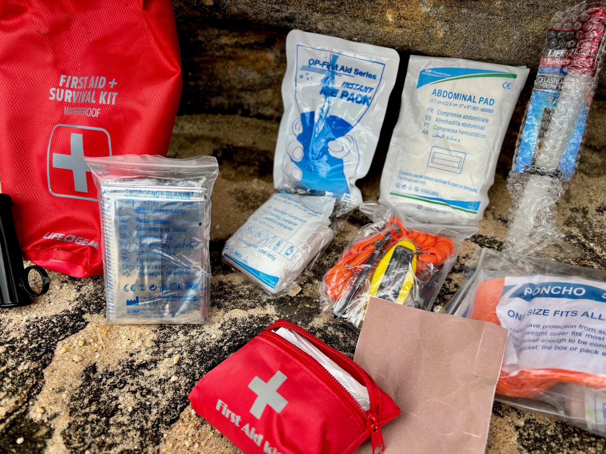 The survival items of the kit: poncho, moleskin, cold compress and dressings in their packets