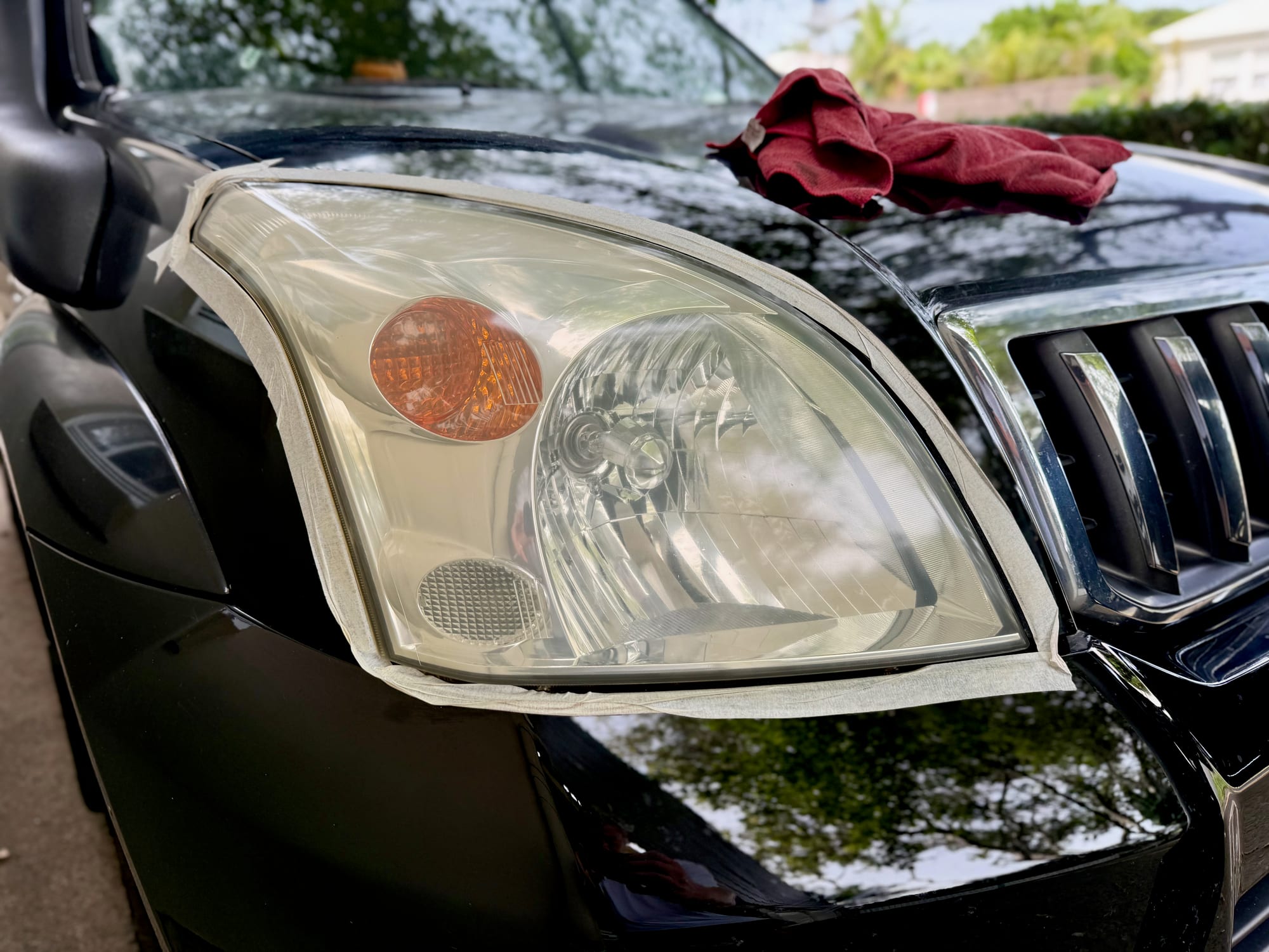 The headlight much clearer after the compound, with the masking tape still around it