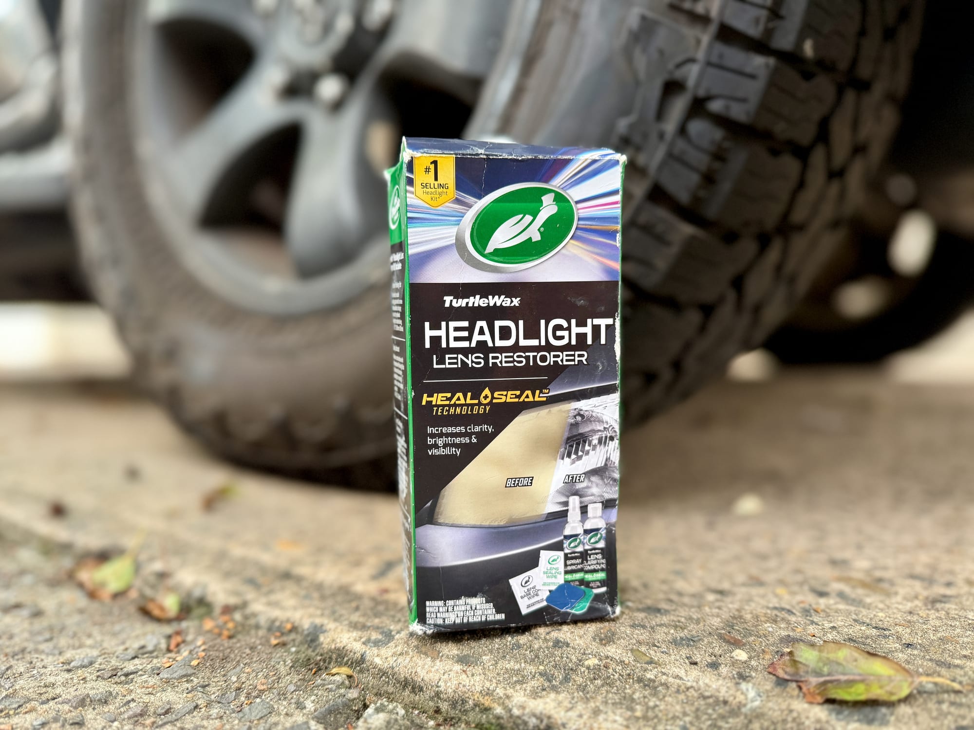 The Turtle Wax Headlight Lens Restorer kit box standing in front of a 4WD wheel