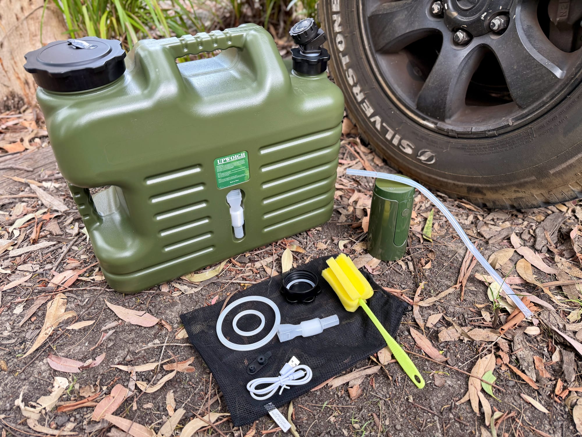 The Upwoigh container with the electric pump, the hose and the kit laid out on a mesh bag in front of it