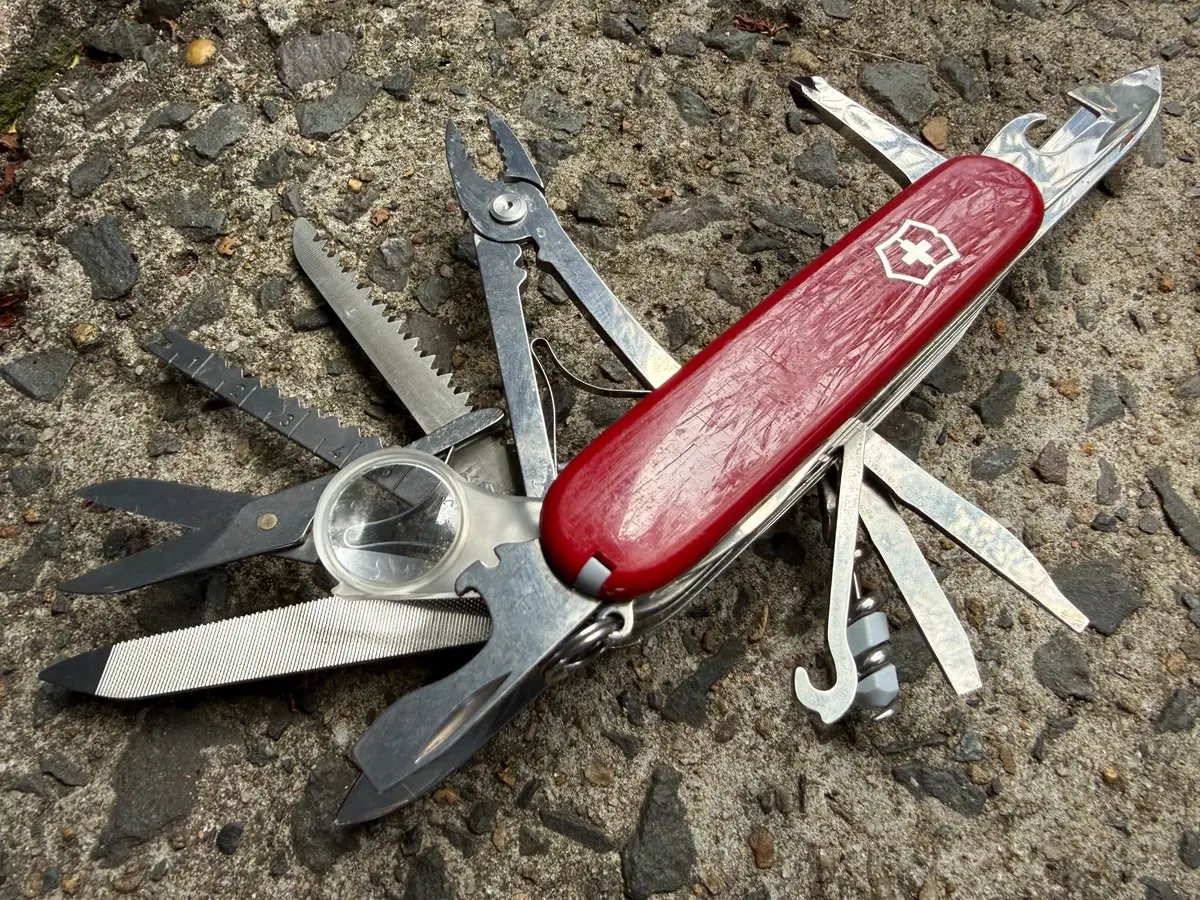 The red Victorinox SwissChamp with all its tools folded out, with numbered dots marking the pliers, saw, scissors, magnifier, file, blade, corkscrew and other tools