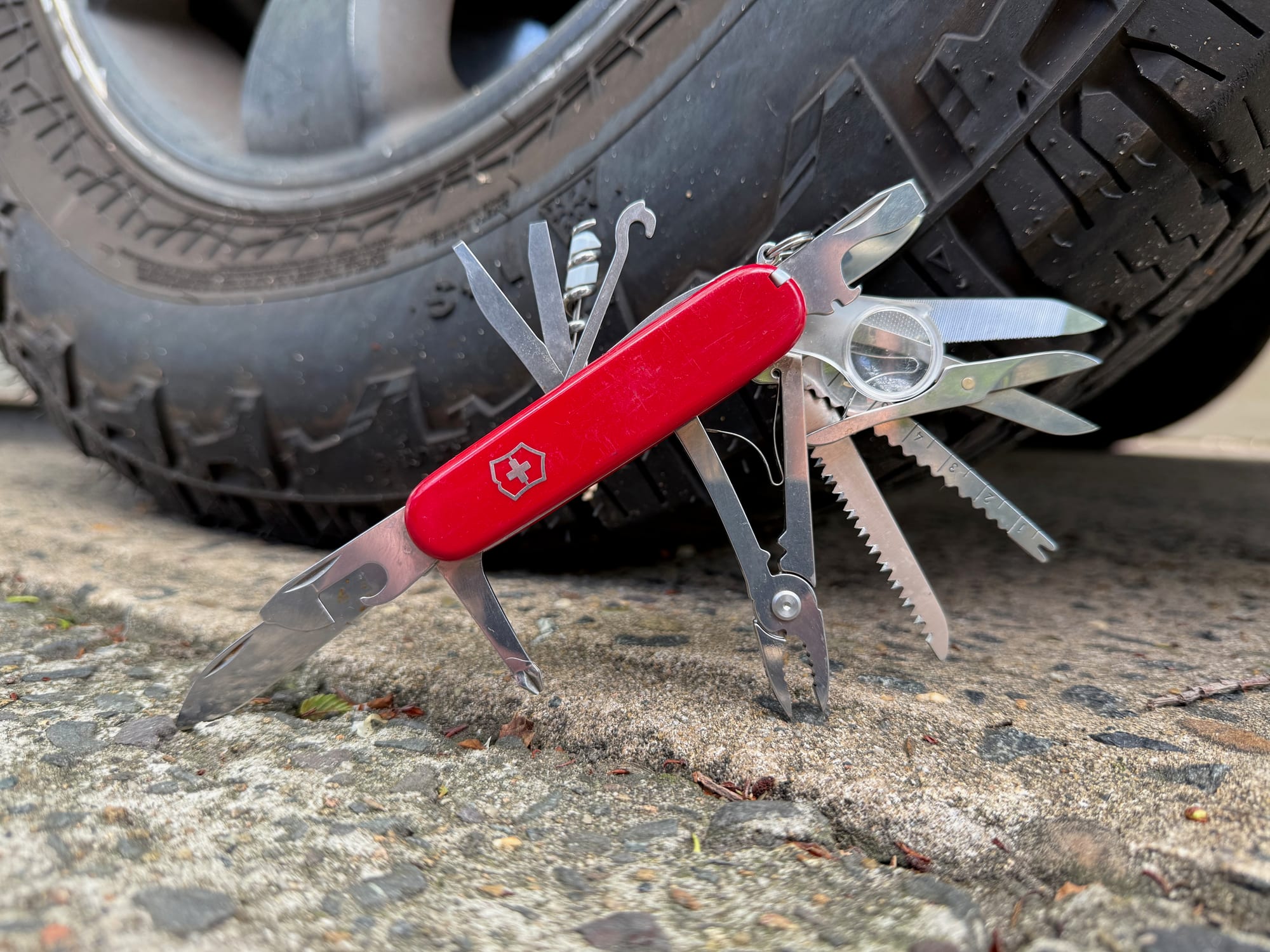The red SwissChamp with its tools folded out, on the ground next to the tyre of our 4WD