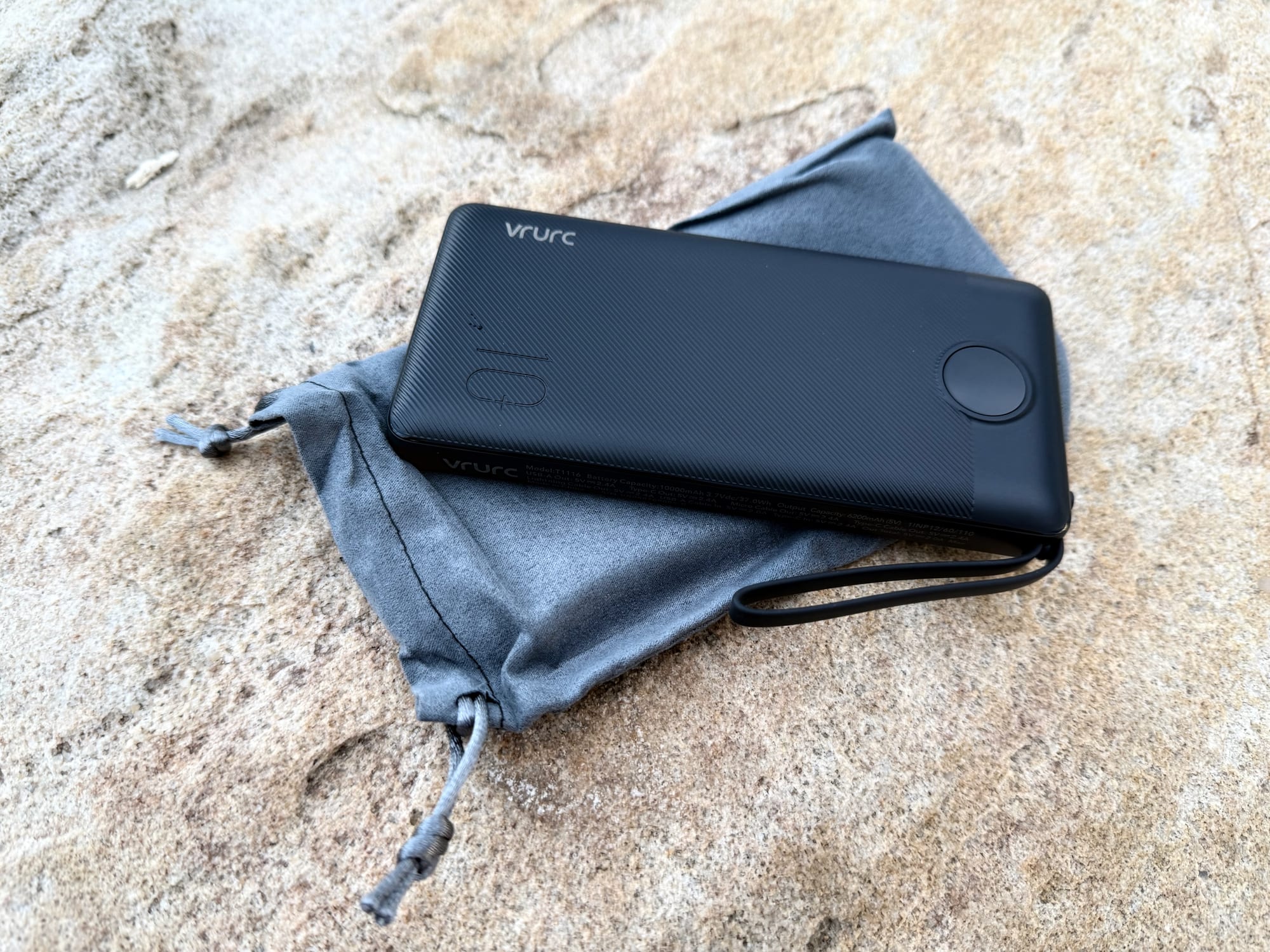 The VRURC 10,000mAh power bank lying on the grey drawstring pouch that comes with it