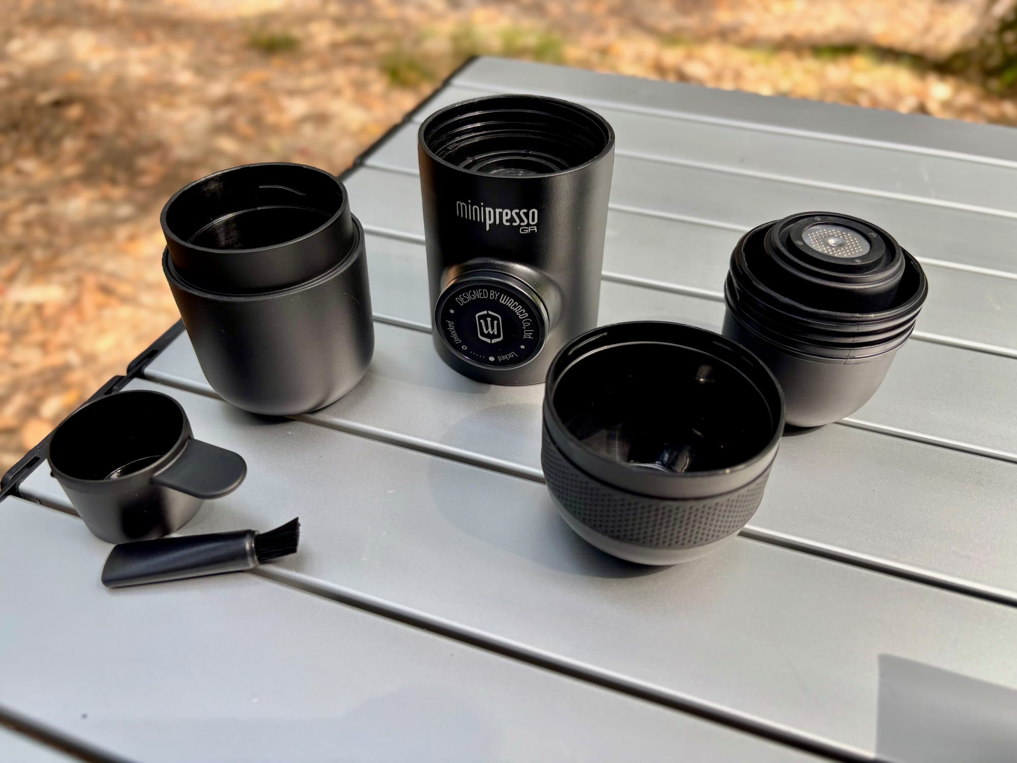 The parts of the Wacaco Minipresso GR: body, water tank, filter basket, cup and scoop