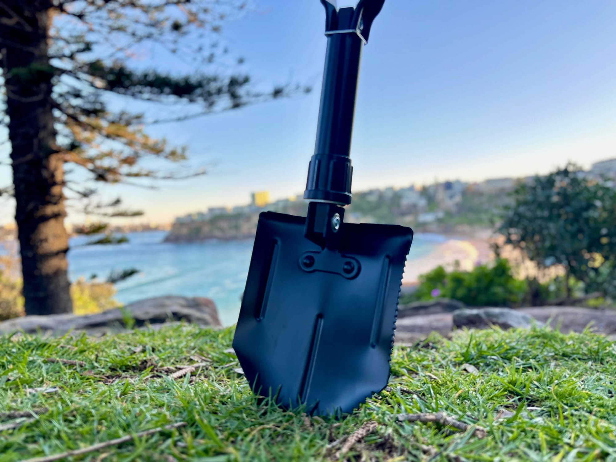 The Wanderer shovel standing upright with its blade in the ground, above a beach