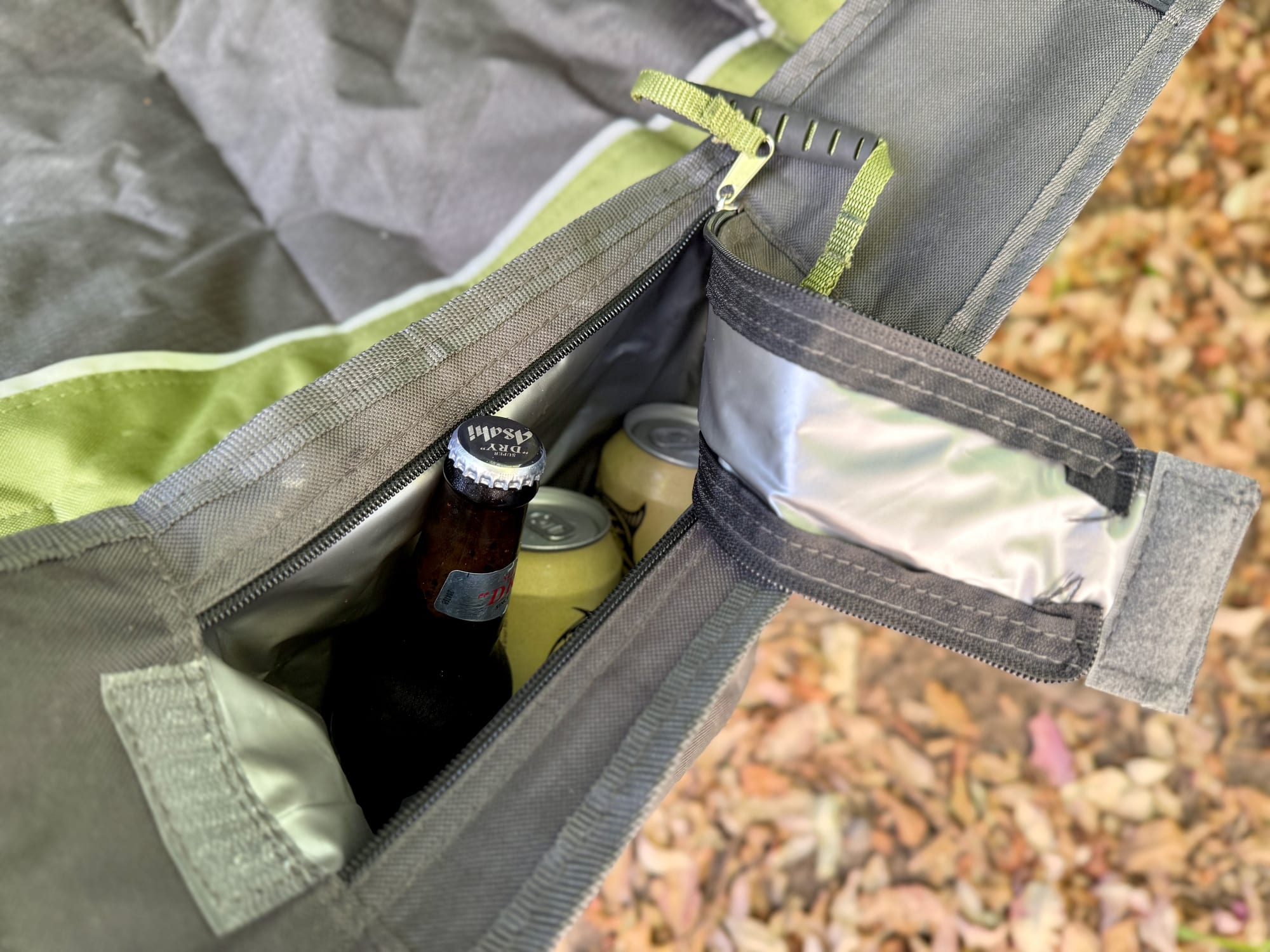 The cooler arm of the Wanderer Premium chair open, with a beer bottle and cans inside